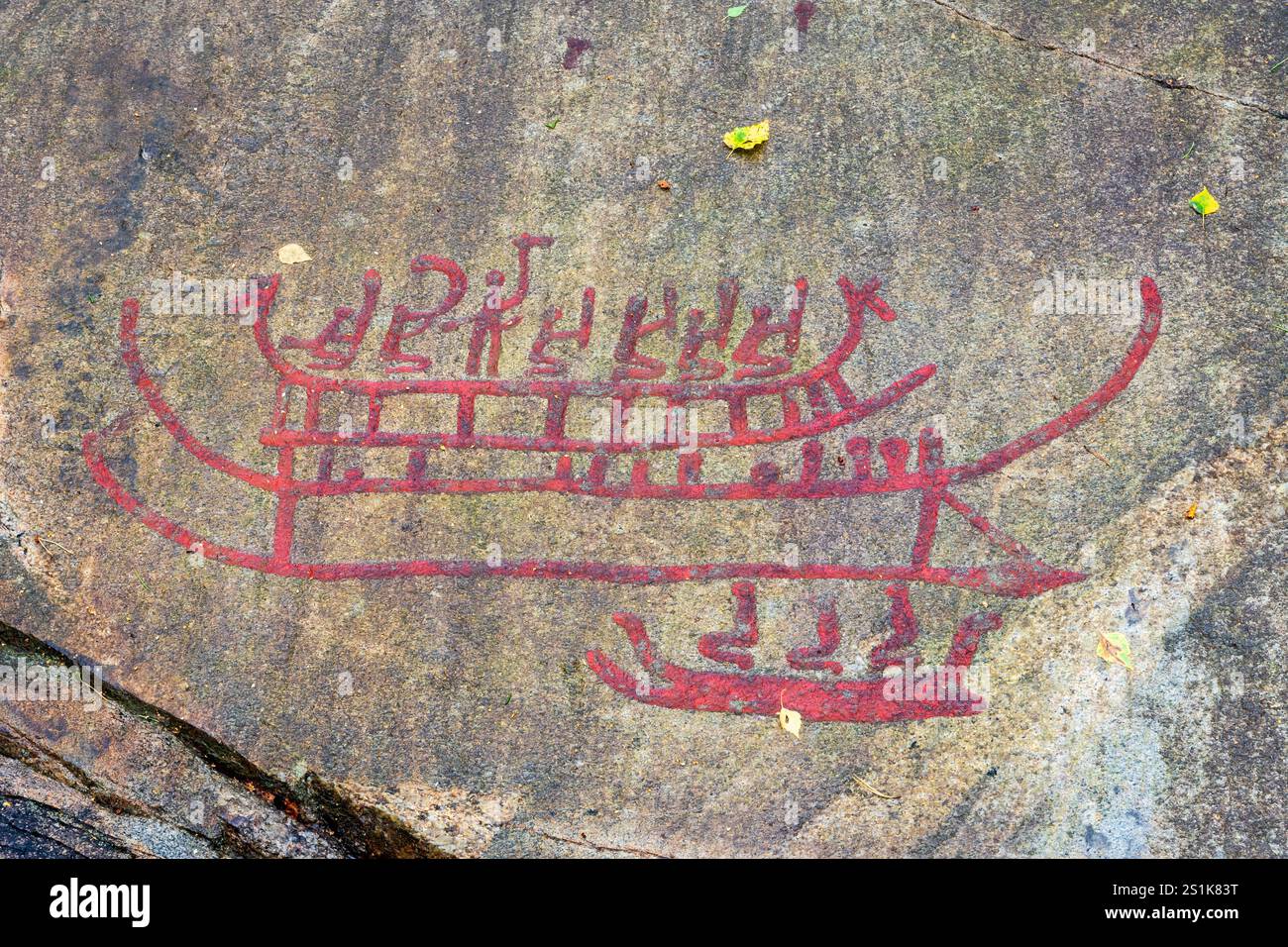 Recopie des sculptures rupestres de Tanum sur la roche plate de Vitlycke, peinte en rouge, représentant des gens sur des bateaux, datant de l'âge du bronze et du fer. Banque D'Images