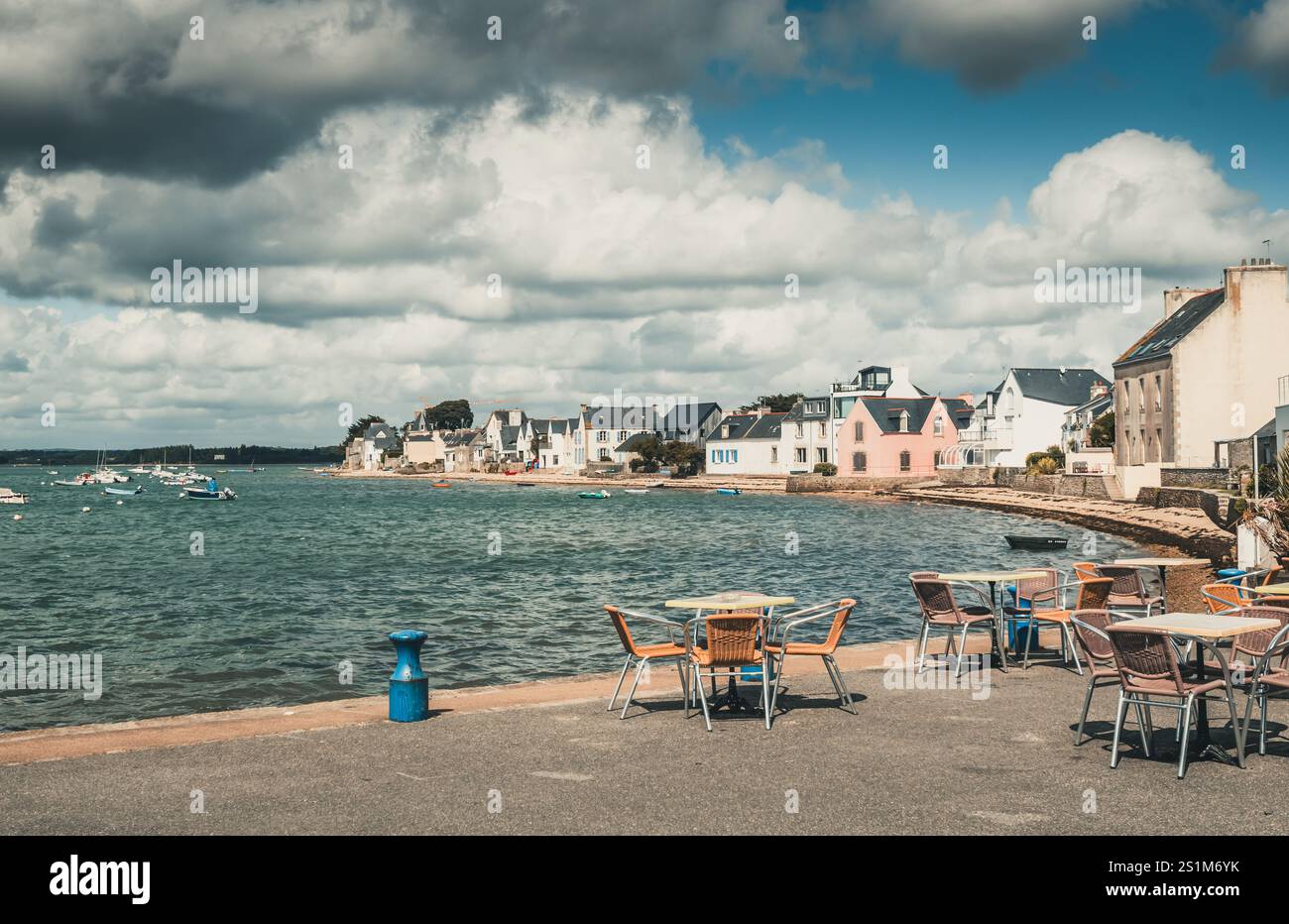 Tables et chaises d'un café sur la jetée d'un village balnéaire, nuageux jour d'été Banque D'Images