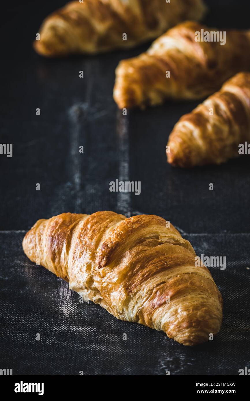 Croissants français frais sur fond noir, vertical Banque D'Images