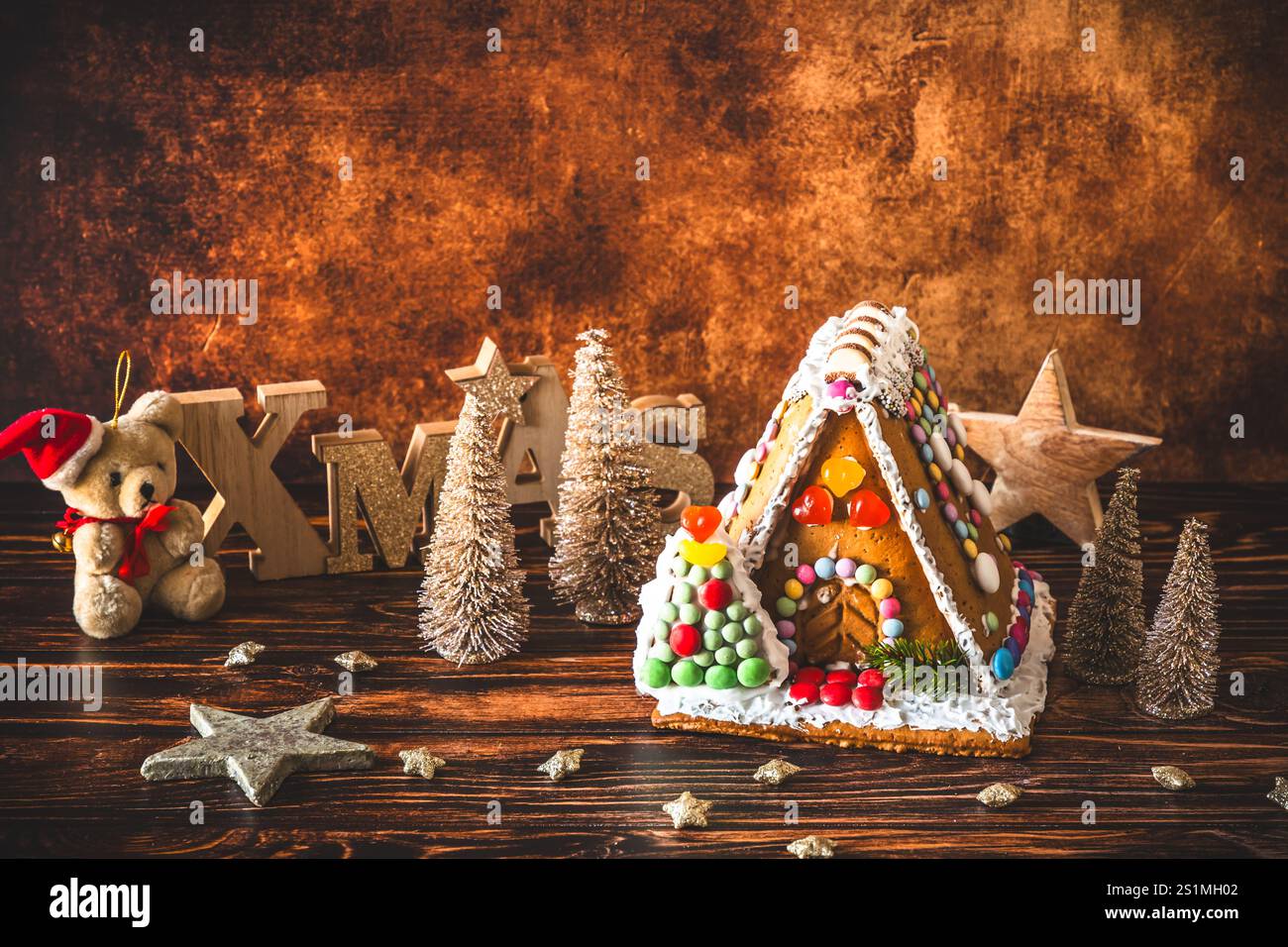 Maison en pain d'épices décorée de bonbons colorés et décoration de noël sur fond de bois. Banque D'Images