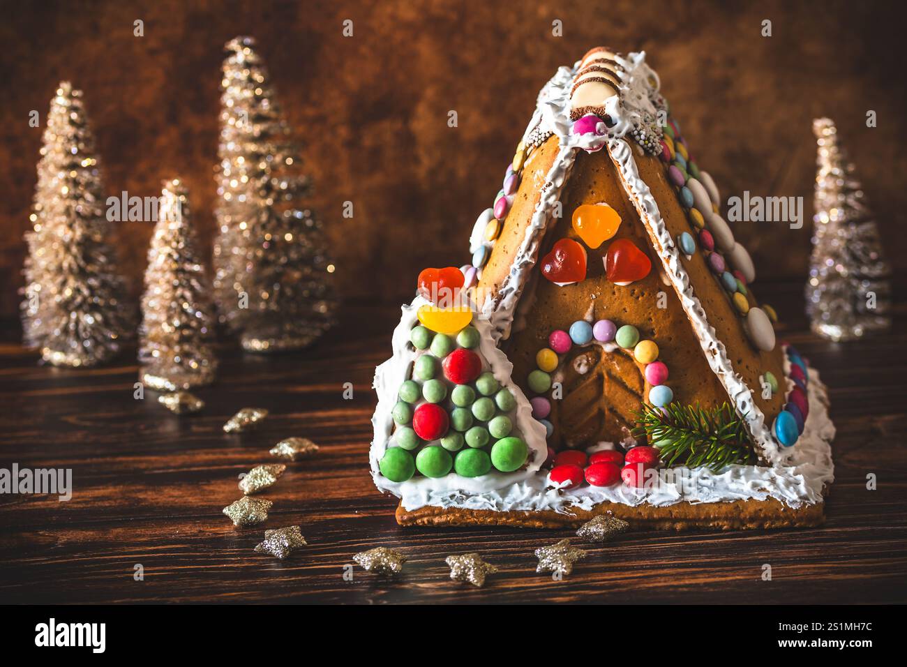 Maison en pain d'épices décorée de bonbons colorés et décoration de noël sur fond de bois. Banque D'Images