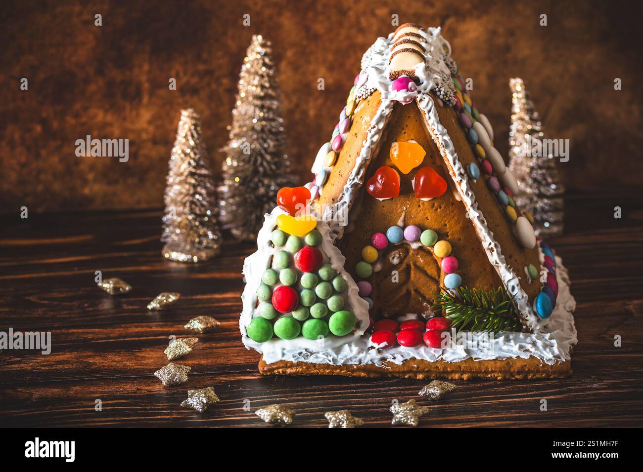 Maison en pain d'épices décorée de bonbons colorés et décoration de noël sur fond de bois. Banque D'Images