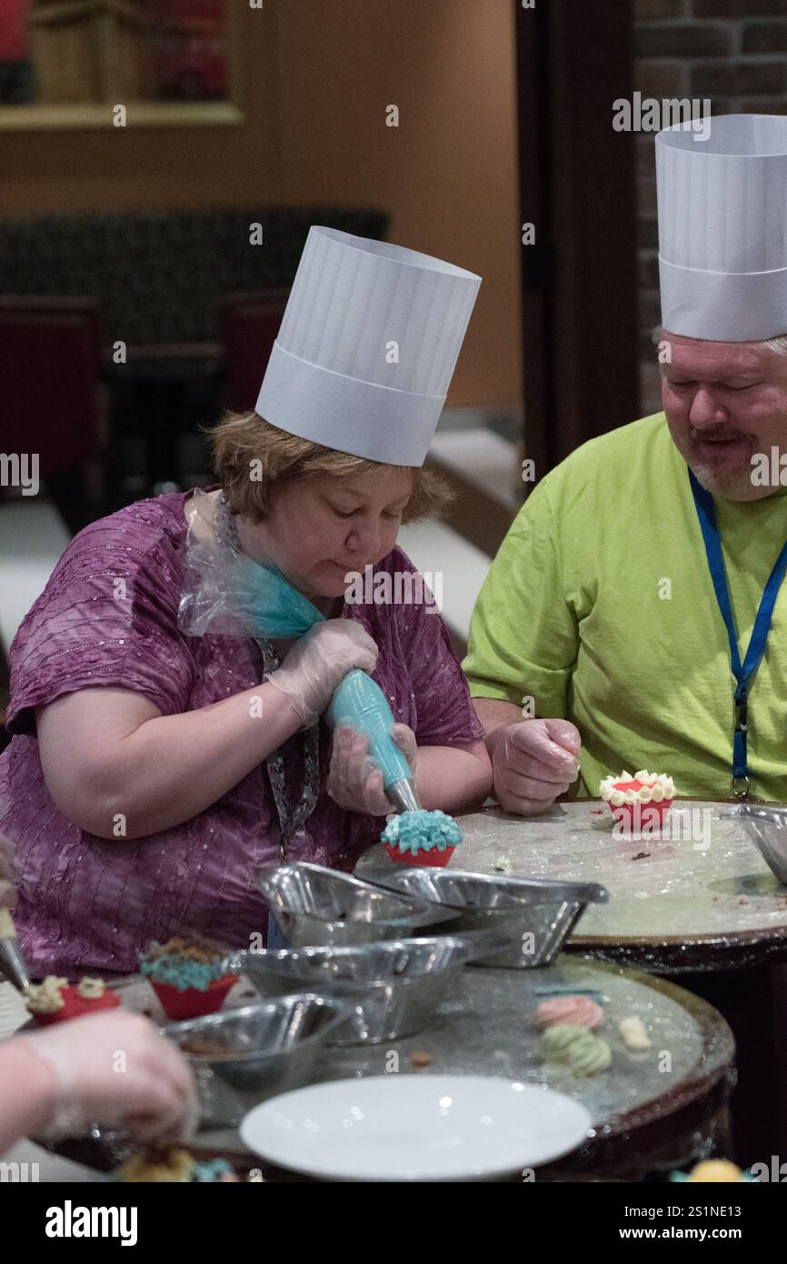 Fort Lauderdale, FL, États-Unis - 27 novembre 2017 : femmes glacant des gâteaux à la classe de décoration de Cupcake Sprinkle Time à bord d'un navire de croisière Royal Caribbean. Banque D'Images