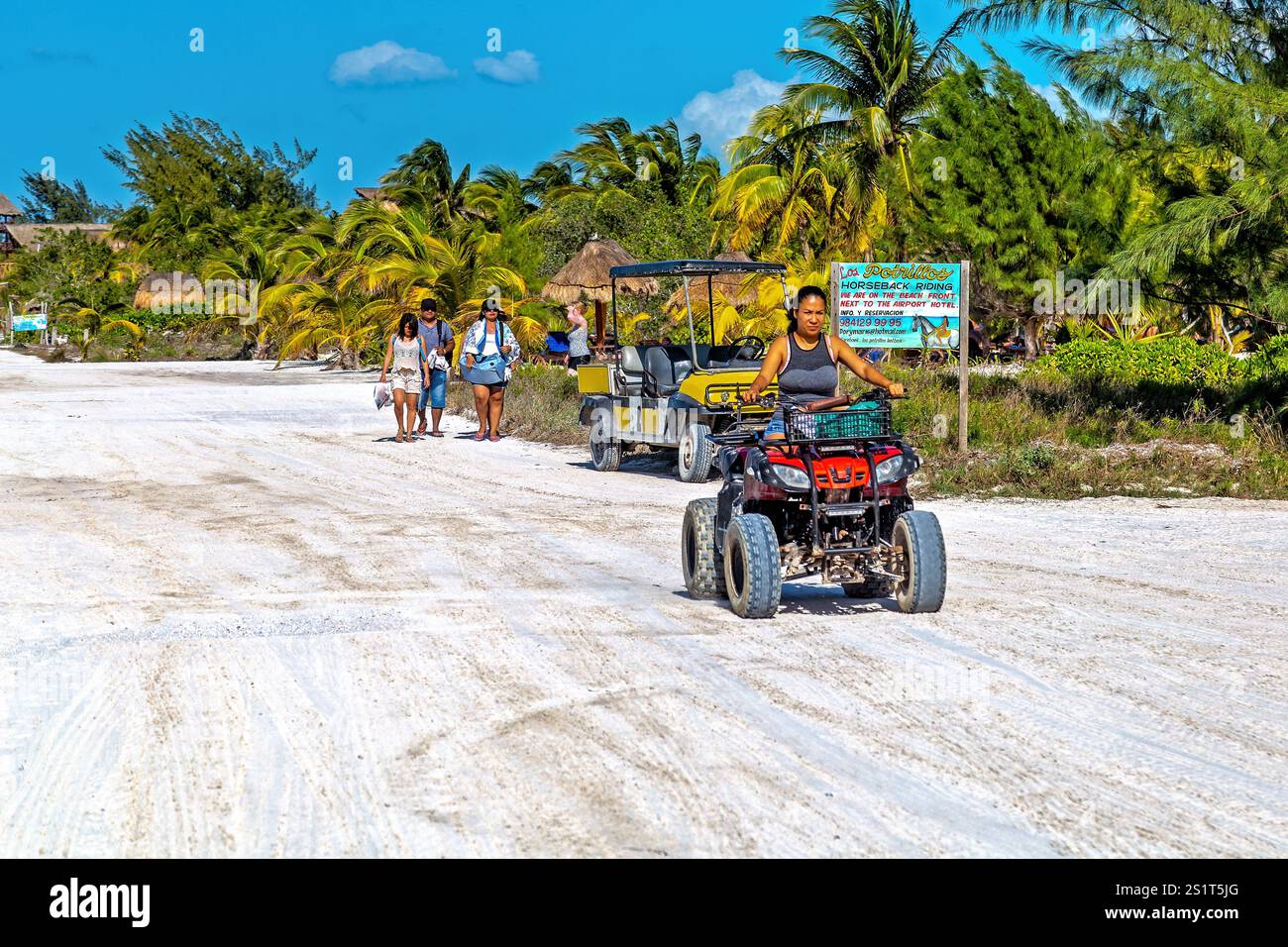 Scène de plage tropicale avec VTT, voiturettes de golf et touristes marchant, Isla Holbox, Mexique Banque D'Images