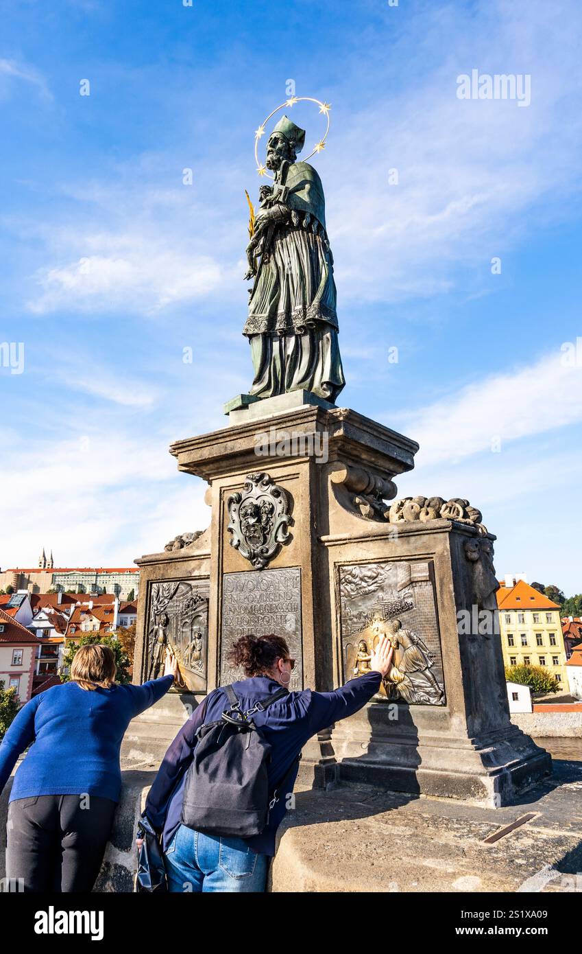 Touristes frottant la statue en bronze de Saint Jean de Nepomuk pour bonne chance, sur le pont Charles, Prague, République tchèque Banque D'Images