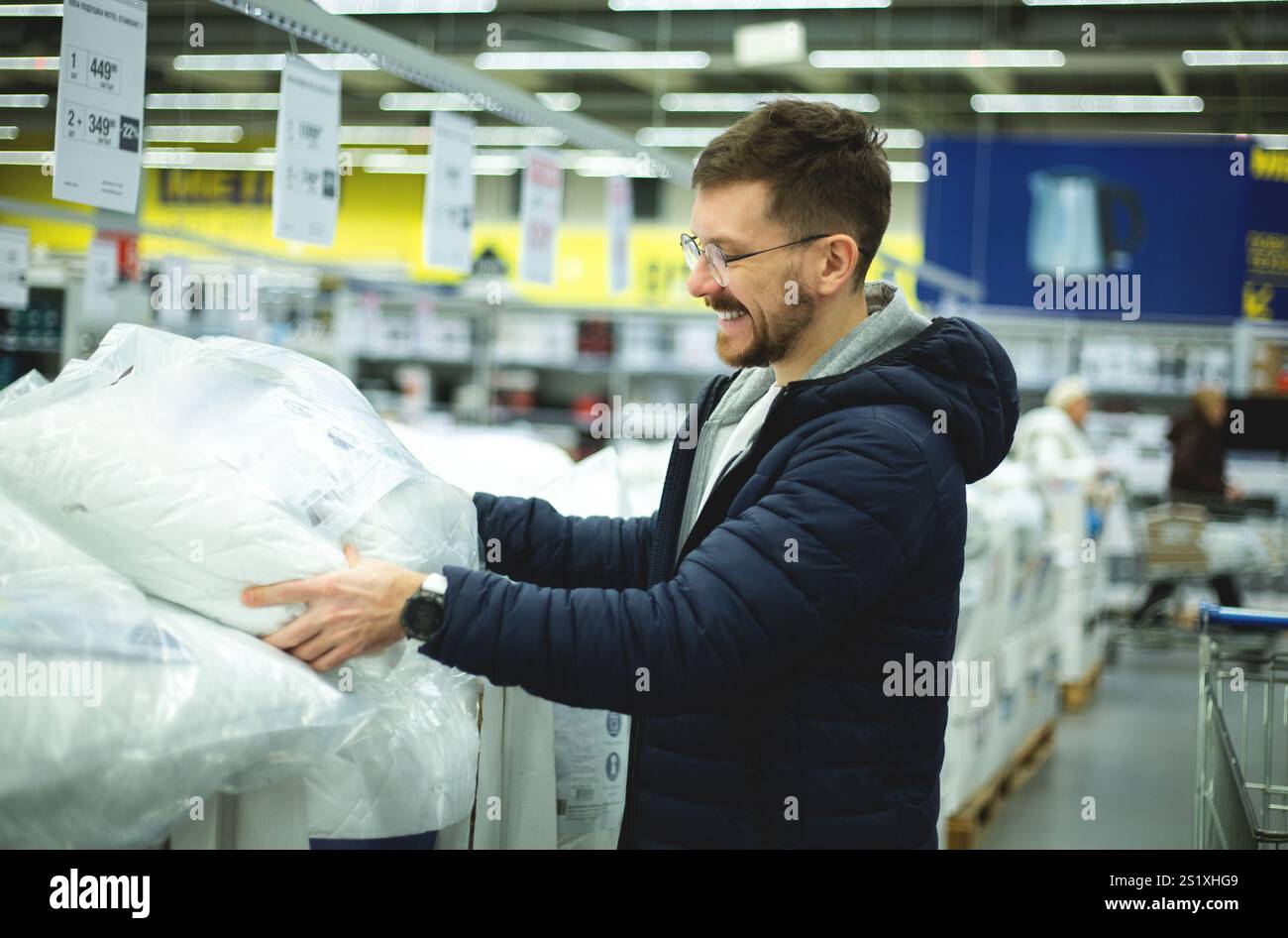 Un homme choisit un oreiller dans un supermarché Banque D'Images