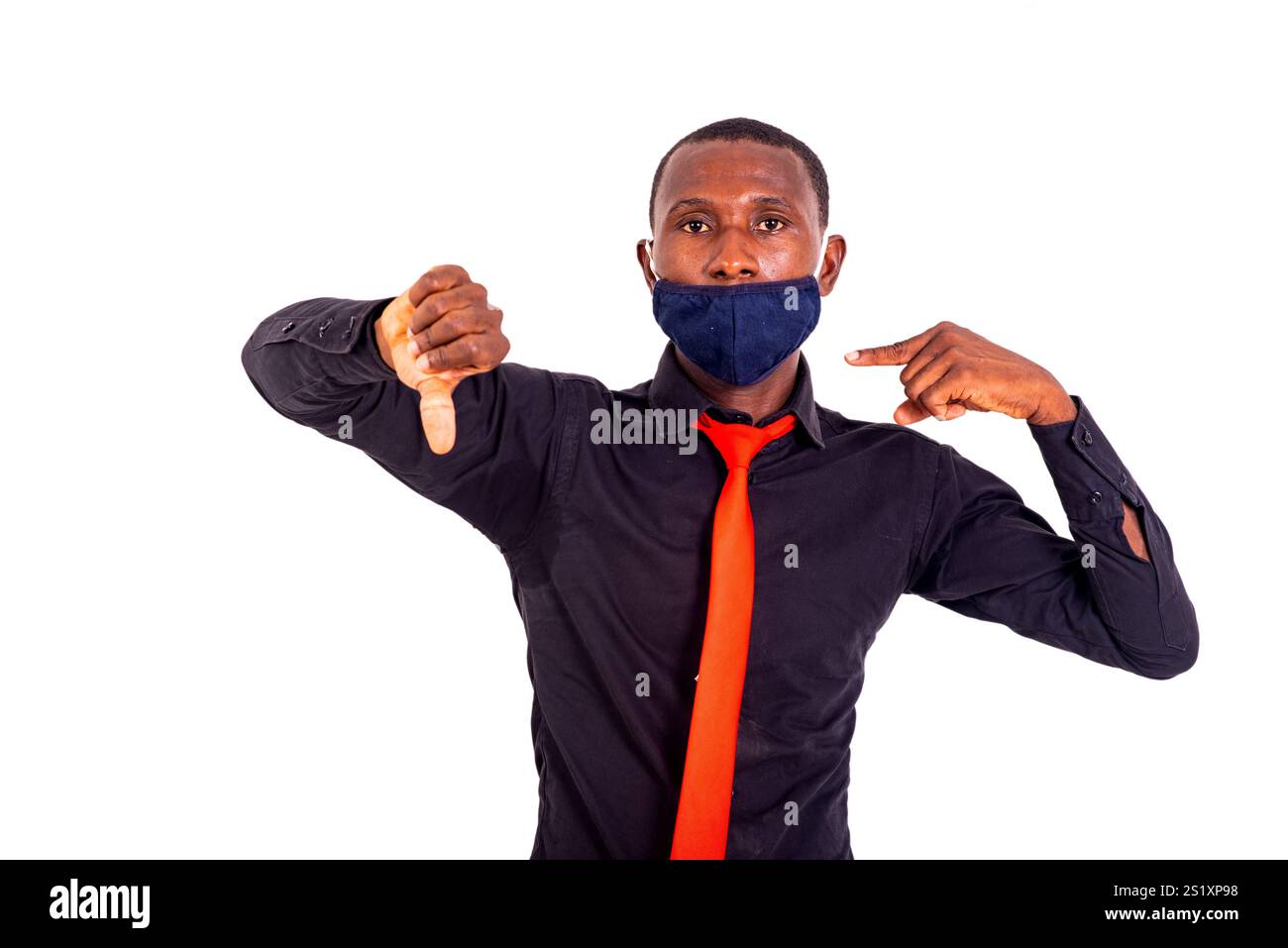 portrait d'un jeune homme d'affaires pointant le pouce vers le bas et montrant un masque médical en tissu avec l'index. Banque D'Images