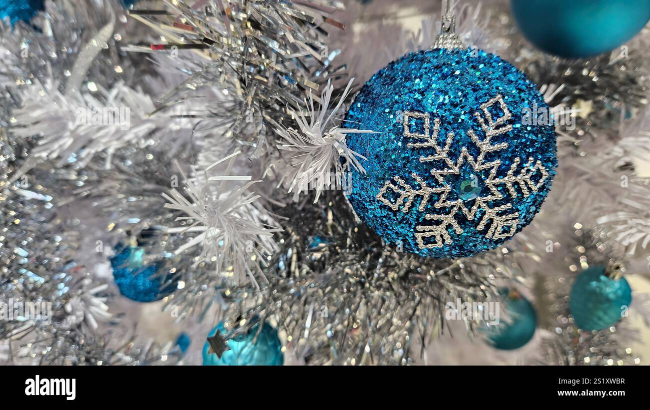 Branches d'arbre de Noël blanc artificiel décorées de belles boules bleues et de guirlandes argentées, gros plan Banque D'Images