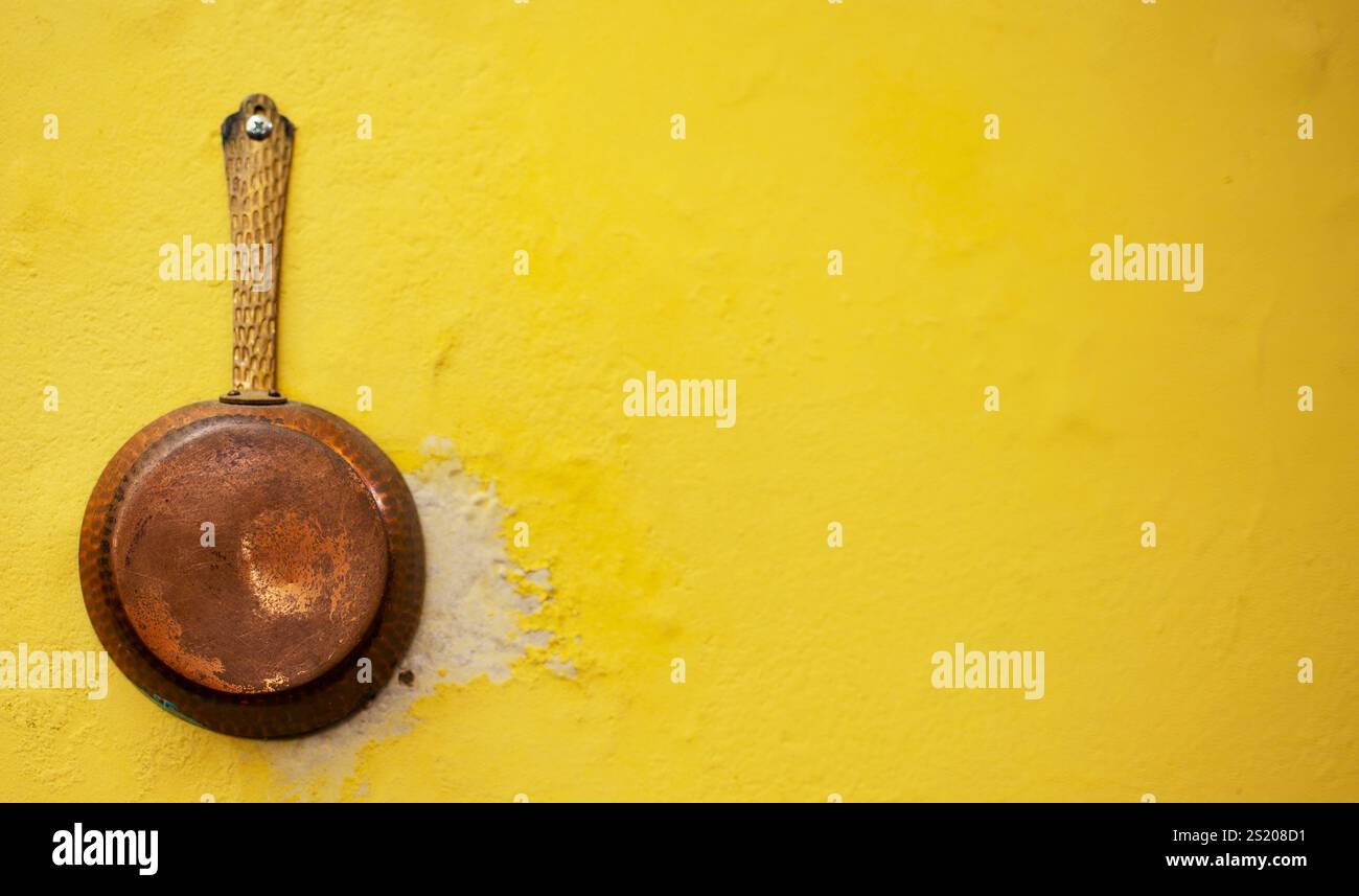 casserole en cuivre accrochée jaune au mur. Journée nationale de la cuisine. JOURNÉE NATIONALE DES CRÊPES 20 Banque D'Images