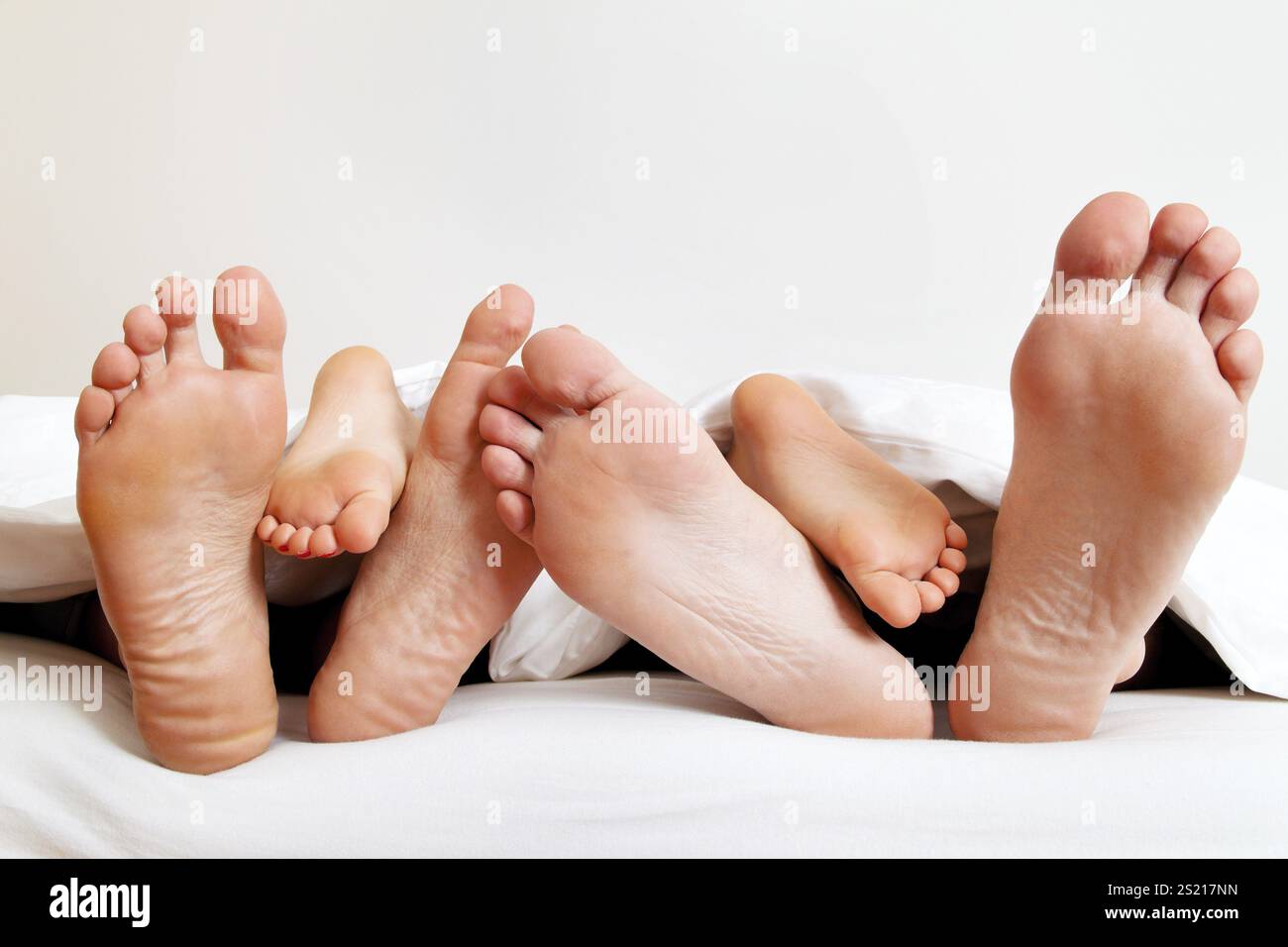 La plante des pieds d'une famille au lit sous les couvertures. Autriche Banque D'Images