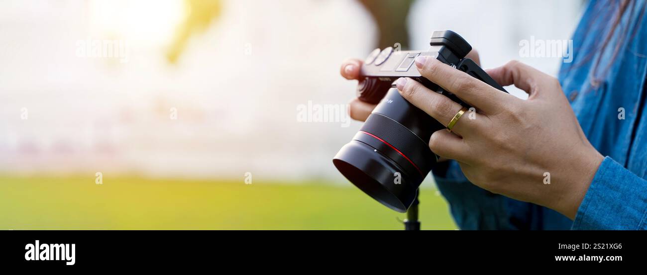 La personne tient la caméra d'action avec microphone par la poignée spéciale, et avec l'autre main ajuste l'affichage pour voir le sujet. Femme photographe tirant avec un Banque D'Images