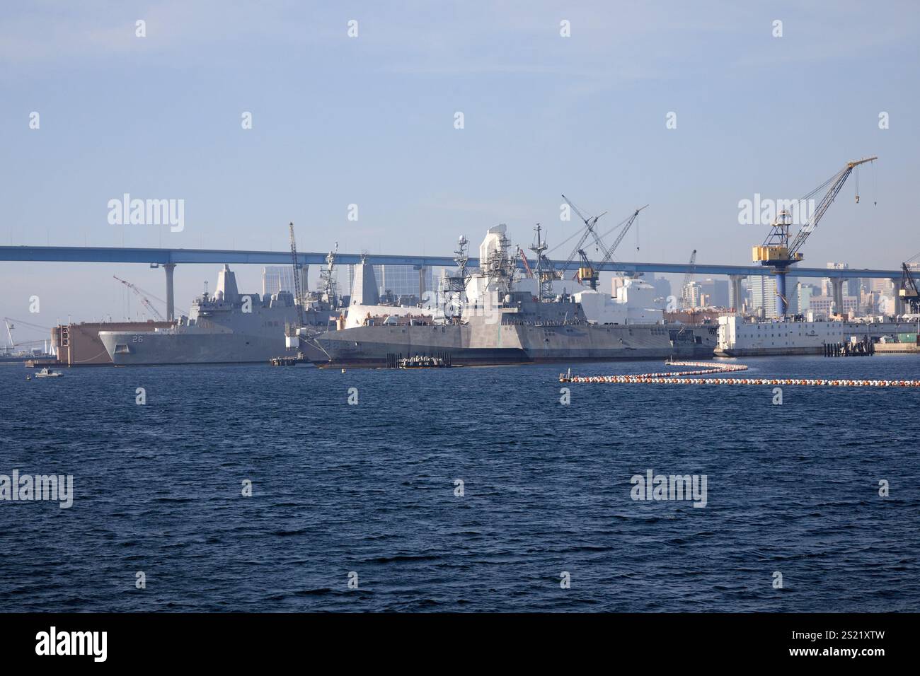 San Diego, Californie, États-Unis. 21 décembre 2024. Une vue d'ensemble de l'USS John P. Murtha (LPD-26), un quai de transport amphibie de la classe San Antonio, amarré près d'une flotte de navires sous l'emblématique Coronado Bridge à San Diego. Les grues et les installations industrielles mettent l'accent sur les activités de construction navale et d'entretien au port. L'horizon de la ville et le pont Coronado créent une toile de fond saisissante, mettant en évidence la juxtaposition de l'infrastructure urbaine et de la puissance navale. (Crédit image : © Ian L. Sitren/ZUMA Press Wire) USAGE ÉDITORIAL SEULEMENT! Non destiné à UN USAGE commercial ! Banque D'Images
