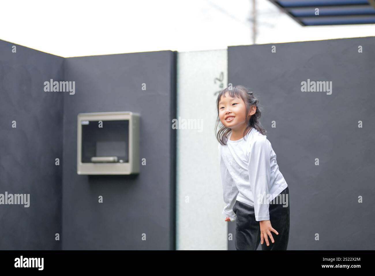 Un parent japonais et un enfant, un homme dans la vingtaine et une fille de 6 ans, jouent en se jetant des balles en plastique vert l'un sur l'autre dans le jardin clôturé de Banque D'Images