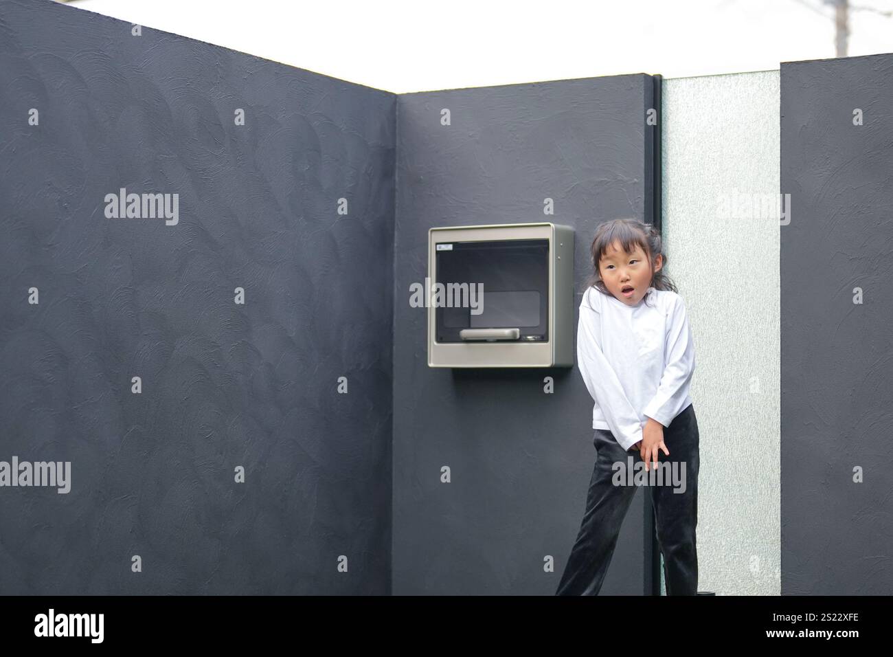 Un parent japonais et un enfant, un homme dans la vingtaine et une fille de 6 ans, jouent en se jetant des balles en plastique vert l'un sur l'autre dans le jardin clôturé de Banque D'Images