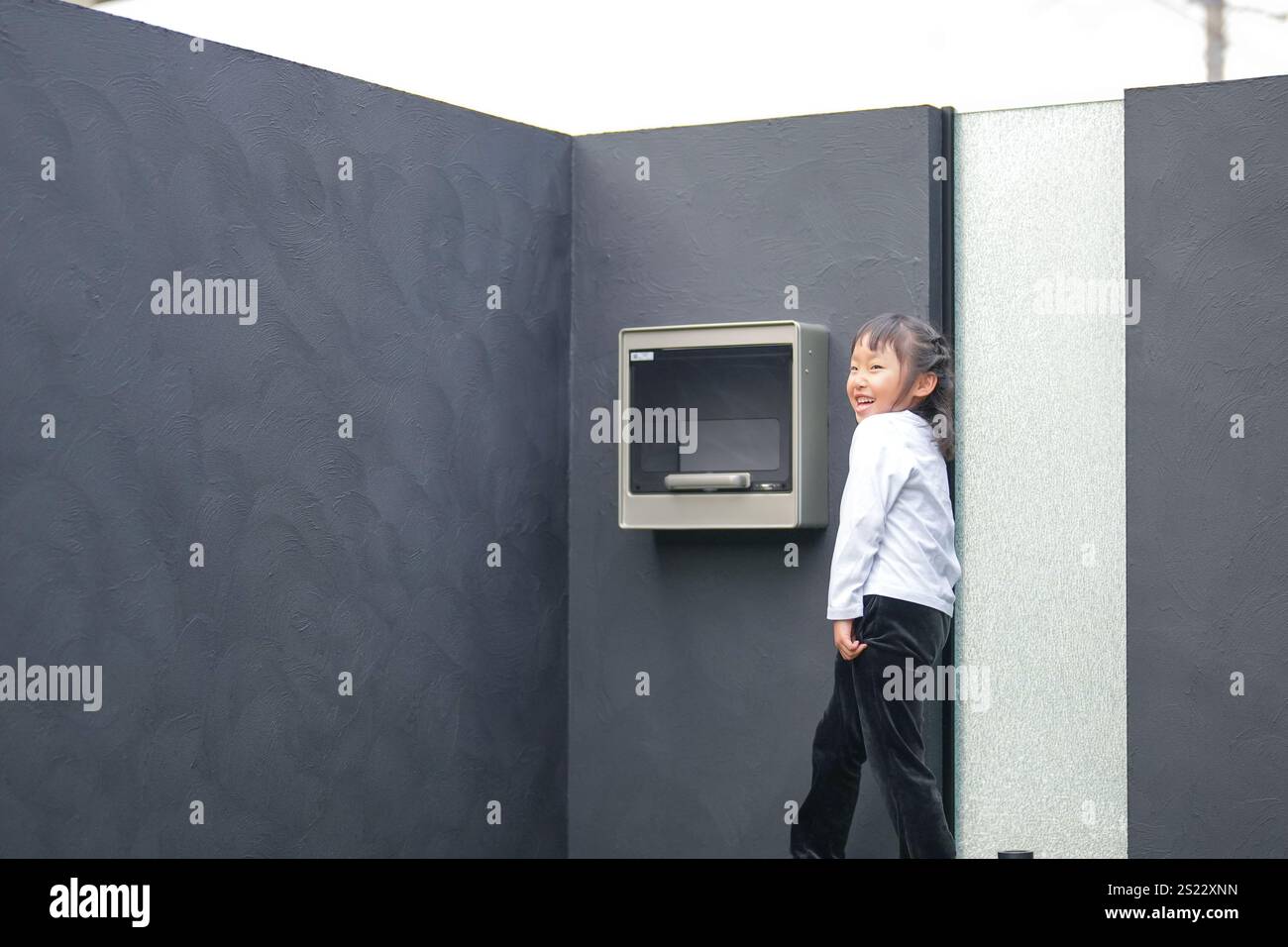 Un parent japonais et un enfant, un homme dans la vingtaine et une fille de 6 ans, jouent en se jetant des balles en plastique vert l'un sur l'autre dans le jardin clôturé de Banque D'Images