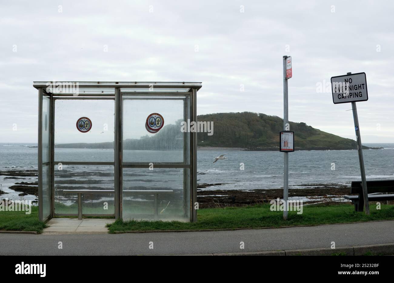Looe, Cornwall, Royaume-Uni - 27 octobre 2021 : arrêt de bus vide avec abri et panneau indiquant pas de camping de nuit et mer et St George's Island en arrière-plan Banque D'Images