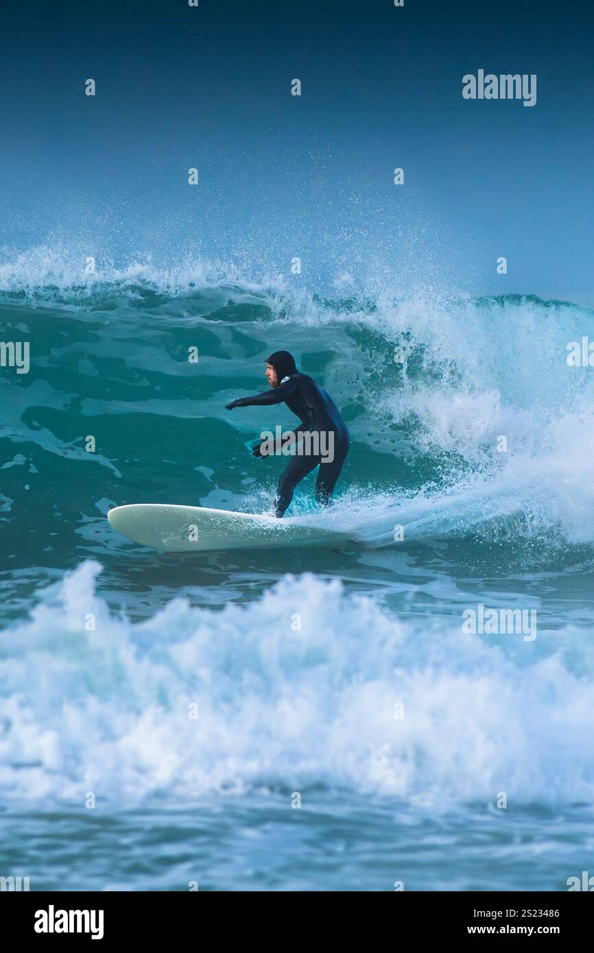 Un surfeur qui fait une vague à Fistral à Newquay, en Cornouailles, au Royaume-Uni. Banque D'Images