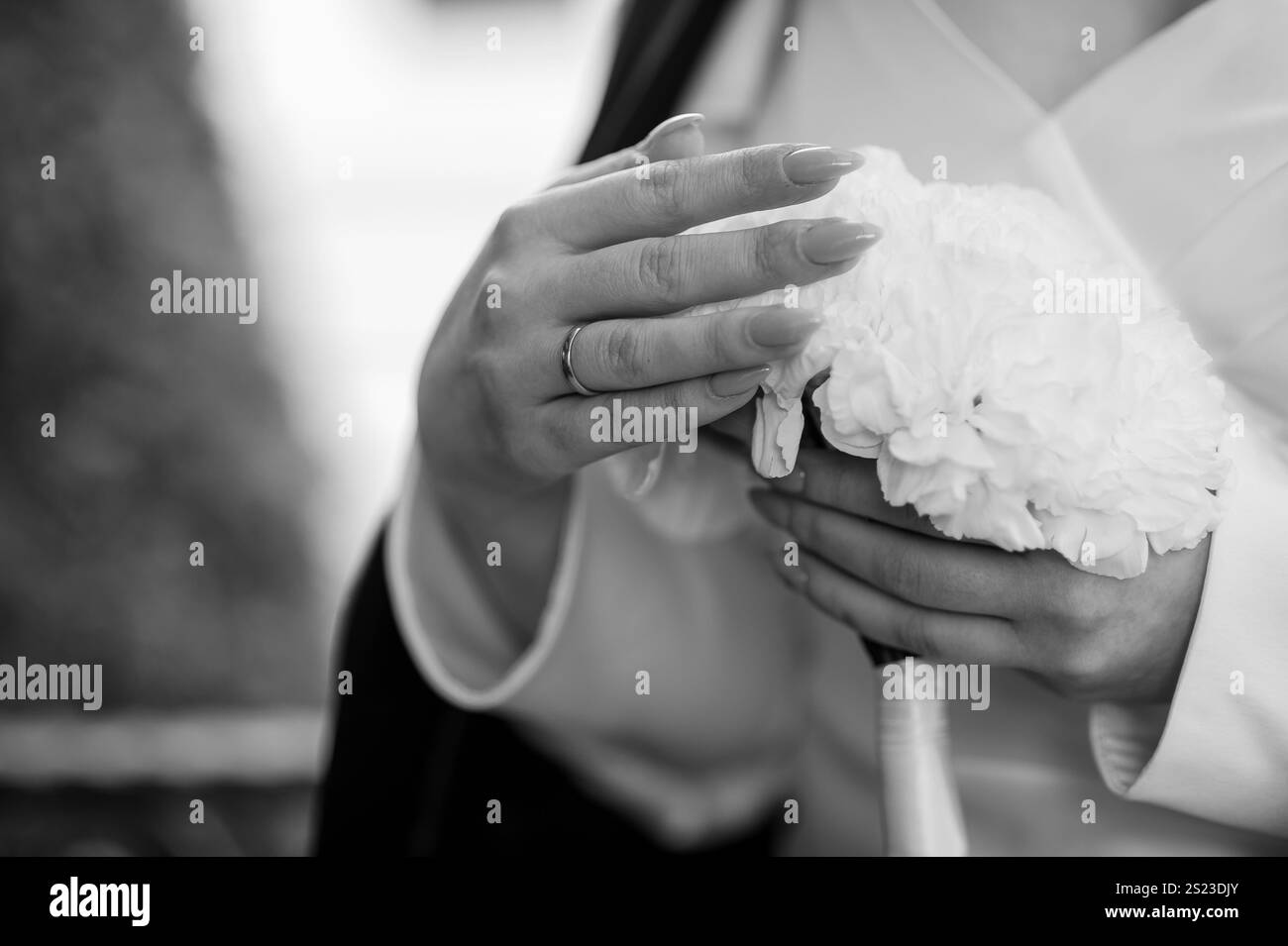 Élégante mariée tenant un bouquet de fleurs blanches en noir et blanc esthétique. Banque D'Images