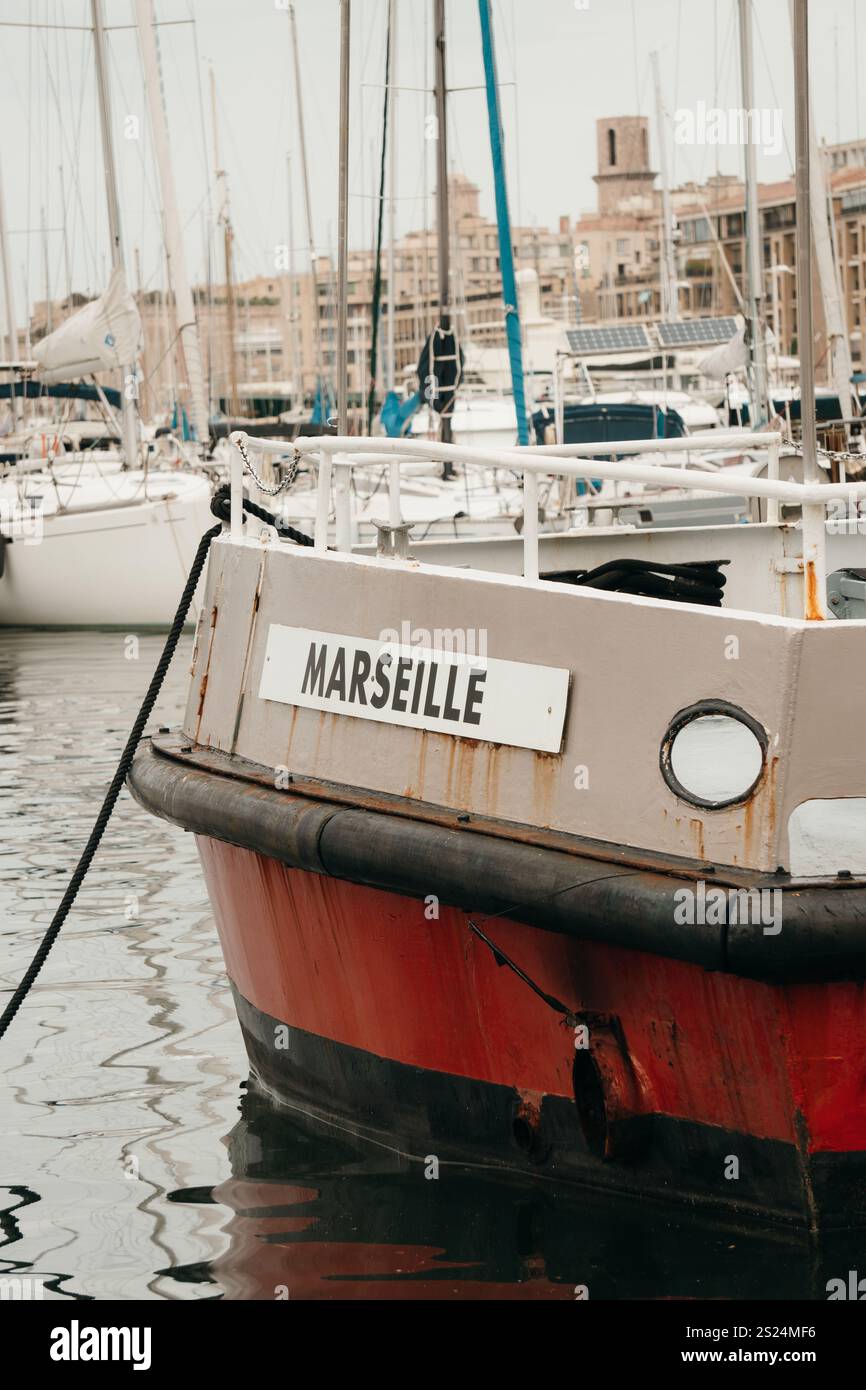 Vue rapprochée d'un bateau amarré dans le port de Marseille, France, avec sa plaque signalétique « MARSEILLE ». L'arrière-plan présente la marina. Banque D'Images