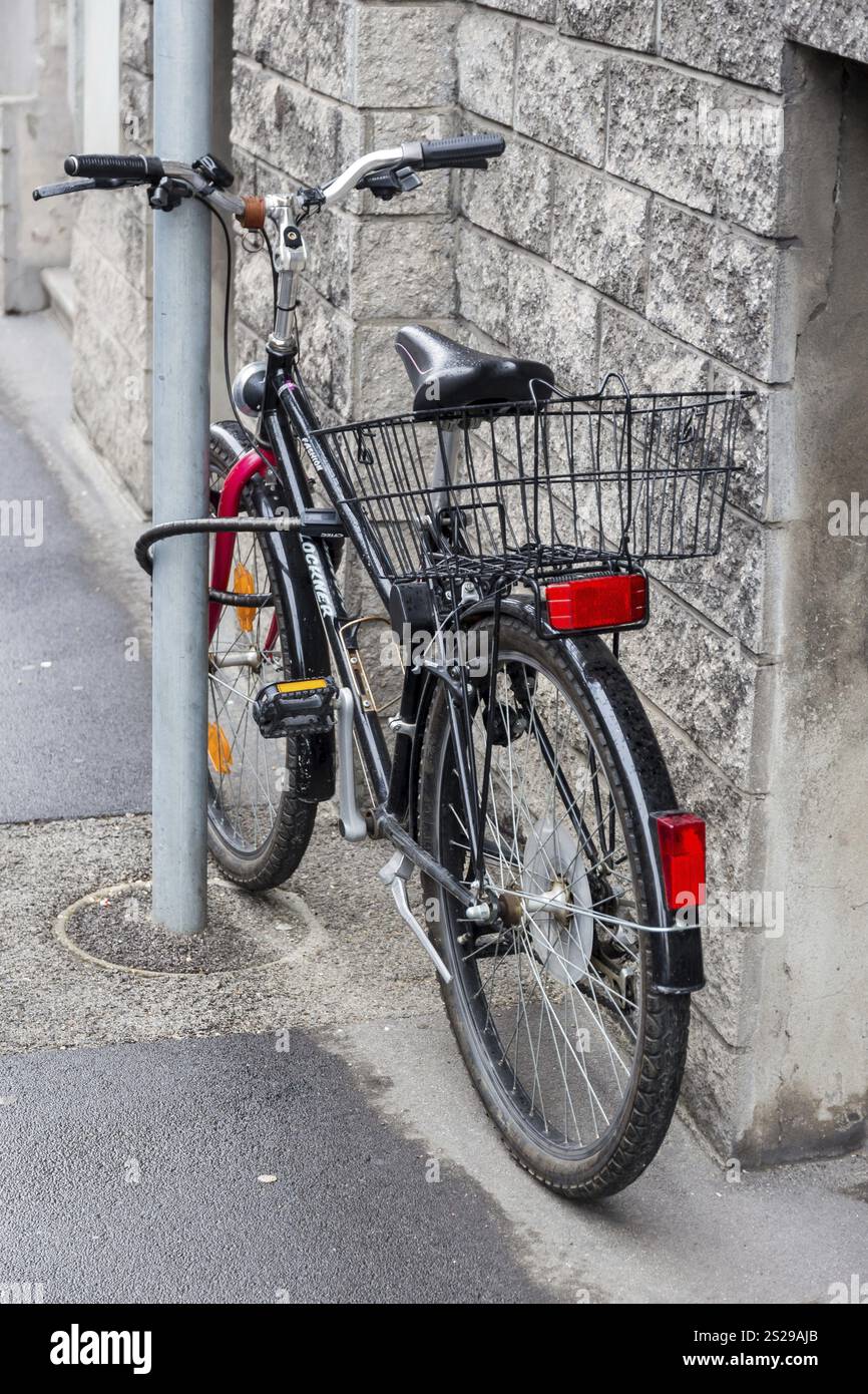Une bicyclette était fixée à un poteau pour la protéger contre le vol. Serrure de bicyclette comme dispositif antivol Autriche Banque D'Images