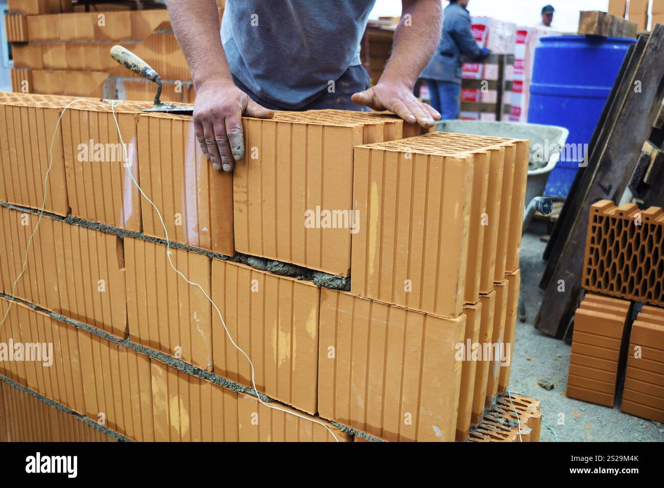 Travailleur de la construction posant une coquille de brique pour une construction solide. Mur de briques d'une maison individuelle Banque D'Images