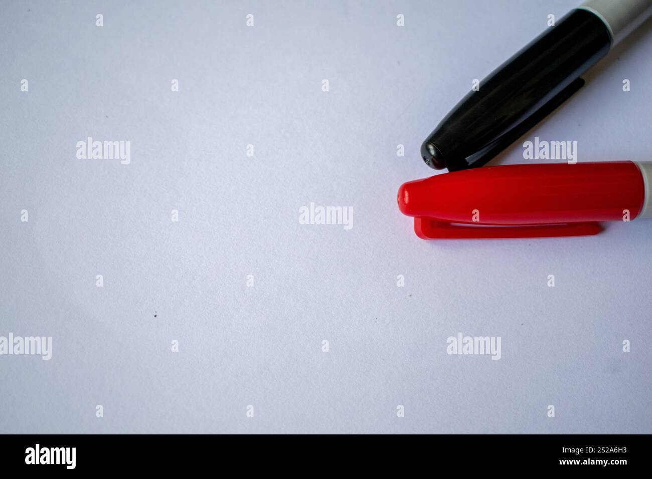 Gros plan d'un marqueur rouge et d'un marqueur noir placés sur une surface blanche et nette, parfait pour mettre en évidence le contraste et la simplicité. Cette image est idéale pour les projets liés à l'éducation, au design, aux fournitures de bureau et à la créativité. L'arrière-plan neutre le rend polyvalent pour une utilisation dans les publicités, le matériel académique et les concepts artistiques Banque D'Images