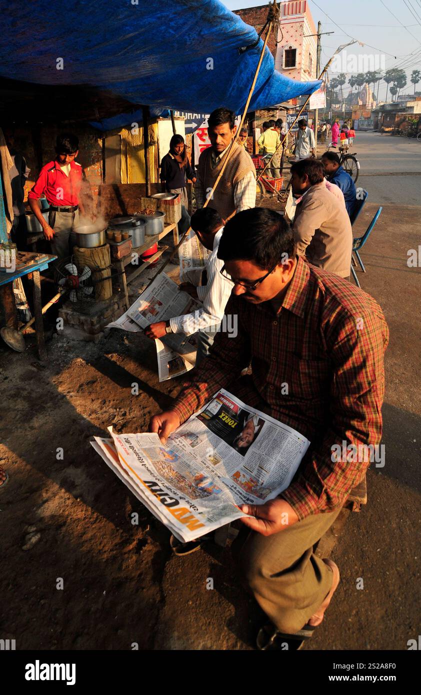 Les hommes locaux dégustant une tasse de chai chaud dans un petit magasin de thé tout en lisant le journal du matin à Ayodhya, Uttar Pradesh, Inde. Banque D'Images