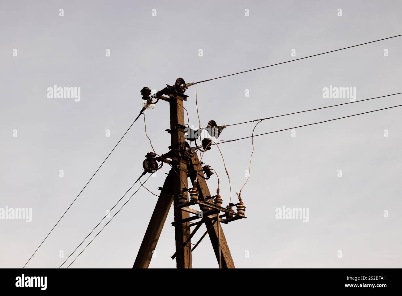 Gros plan de la partie supérieure d'un poteau électrique avec des lignes électriques s'étendant à travers le ciel Banque D'Images