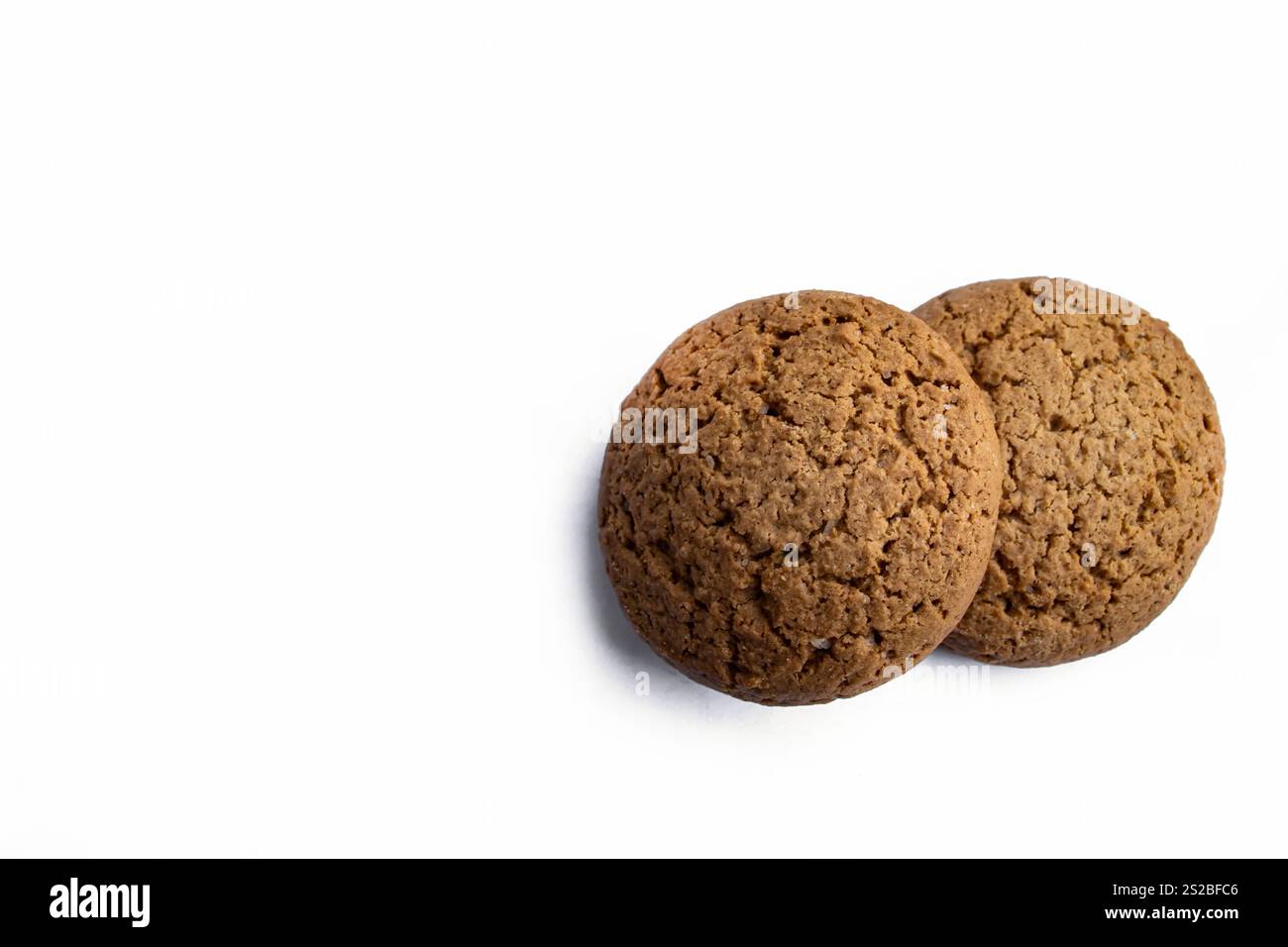 Deux biscuits ronds à l'avoine reposant sur un fond blanc propre, soulignant leur texture dorée et leur charme maison. Banque D'Images
