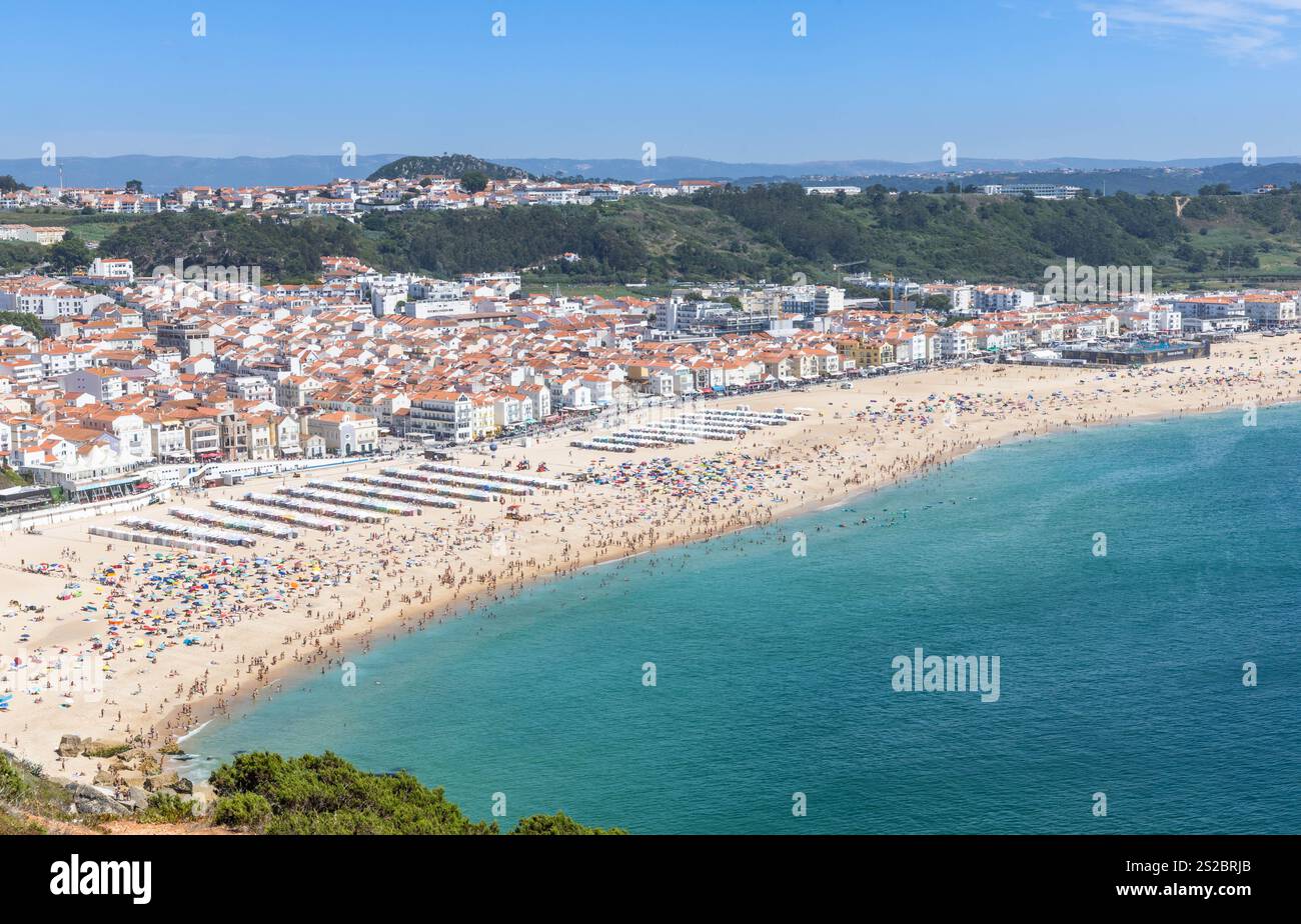 Nazaré plage de sable, boulevard et collines sur une journée d'été avec une plage pleine de gens à Nazare Portugal. Banque D'Images
