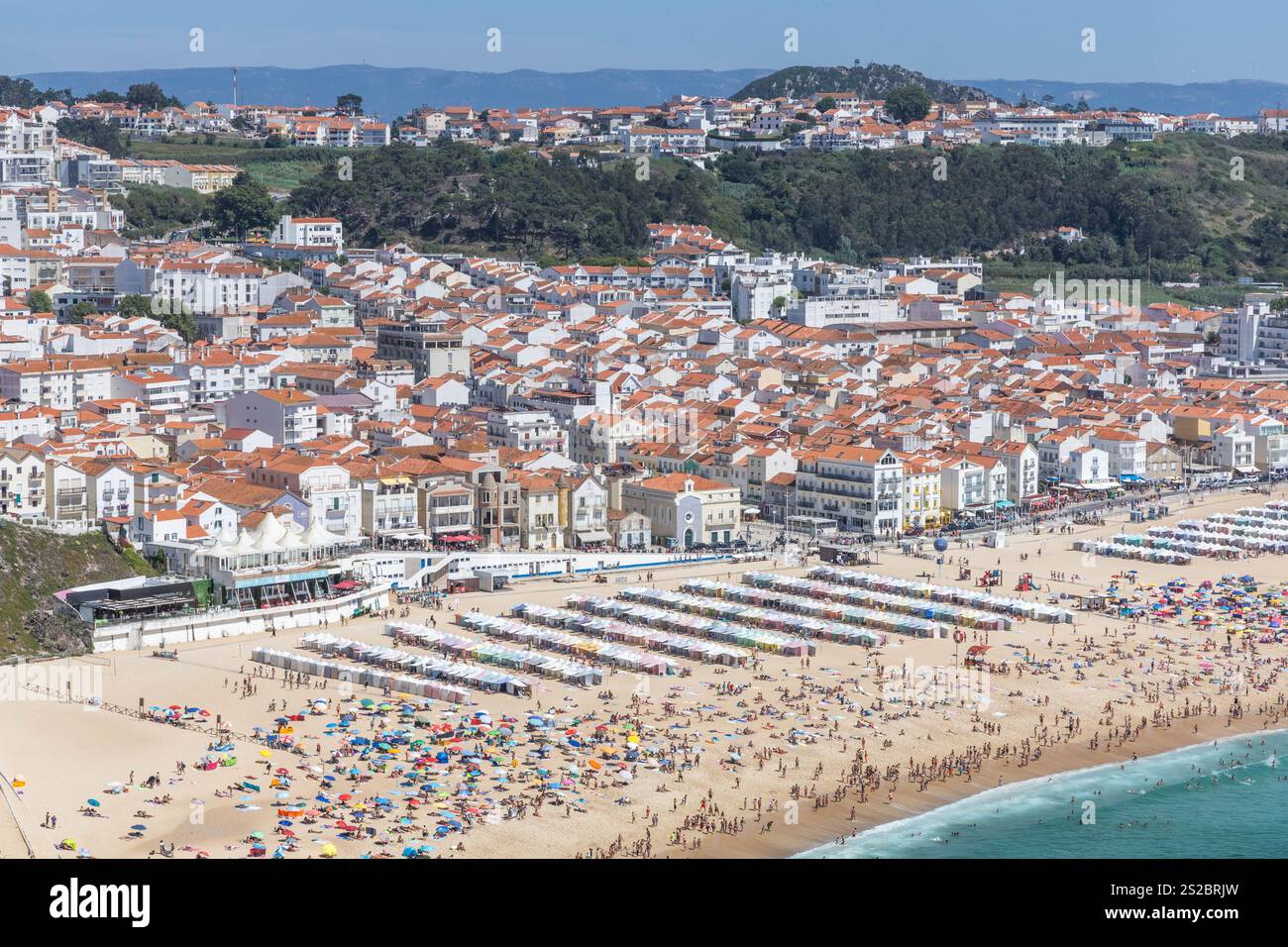 Nazaré plage de sable, boulevard et collines sur une journée d'été avec une plage pleine de gens à Nazare Portugal. Banque D'Images