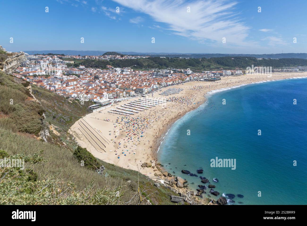 Nazaré plage de sable et collines un jour d'été avec une plage pleine de gens à Nazare Portugal. Banque D'Images