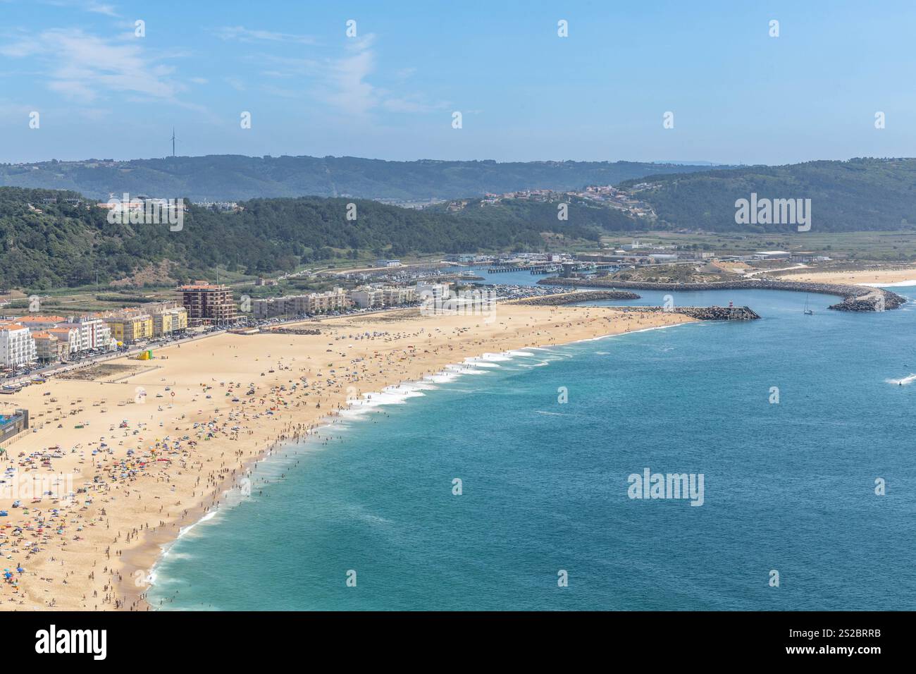 Plage, port et collines un jour d'été avec beaucoup de gens sur la plage de Nazare Portugal. Banque D'Images