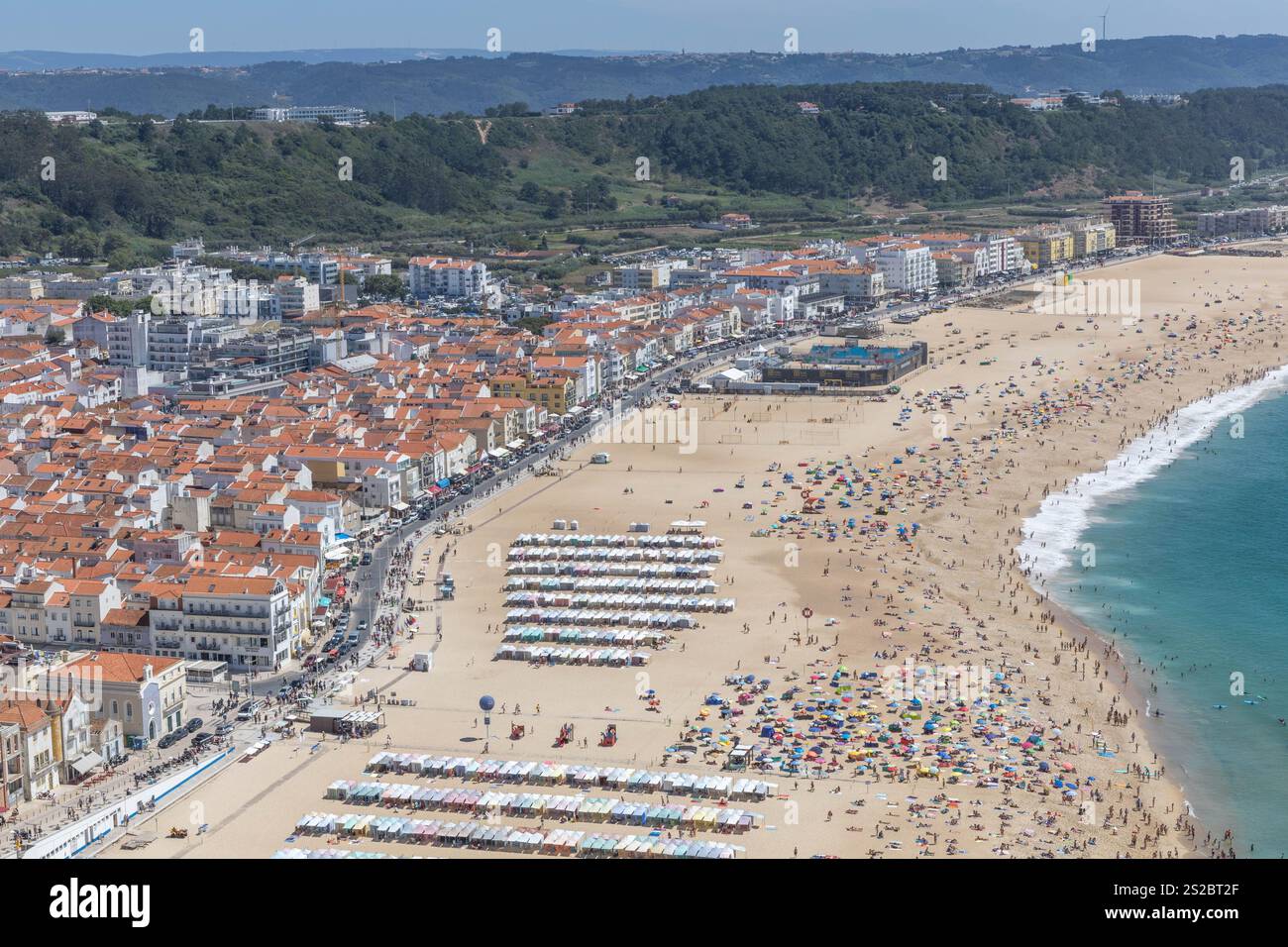 Nazaré plage de sable, boulevard et collines sur une journée d'été avec une plage pleine de gens à Nazare Portugal. Banque D'Images