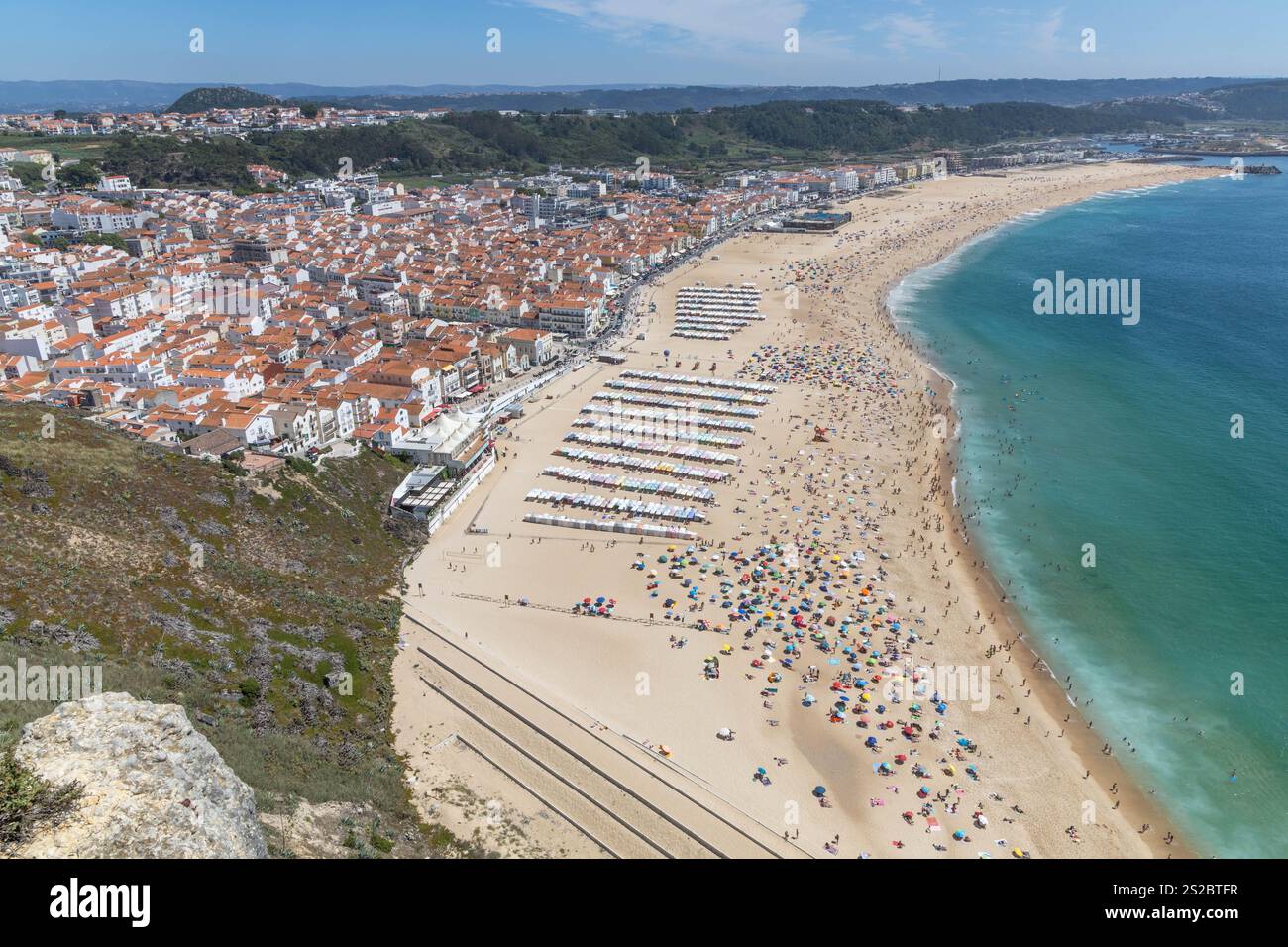 Panorama Nazaré plage de sable, boulevard, collines et océan sur une journée d'été avec une plage pleine de gens à Nazare Portugal. Banque D'Images
