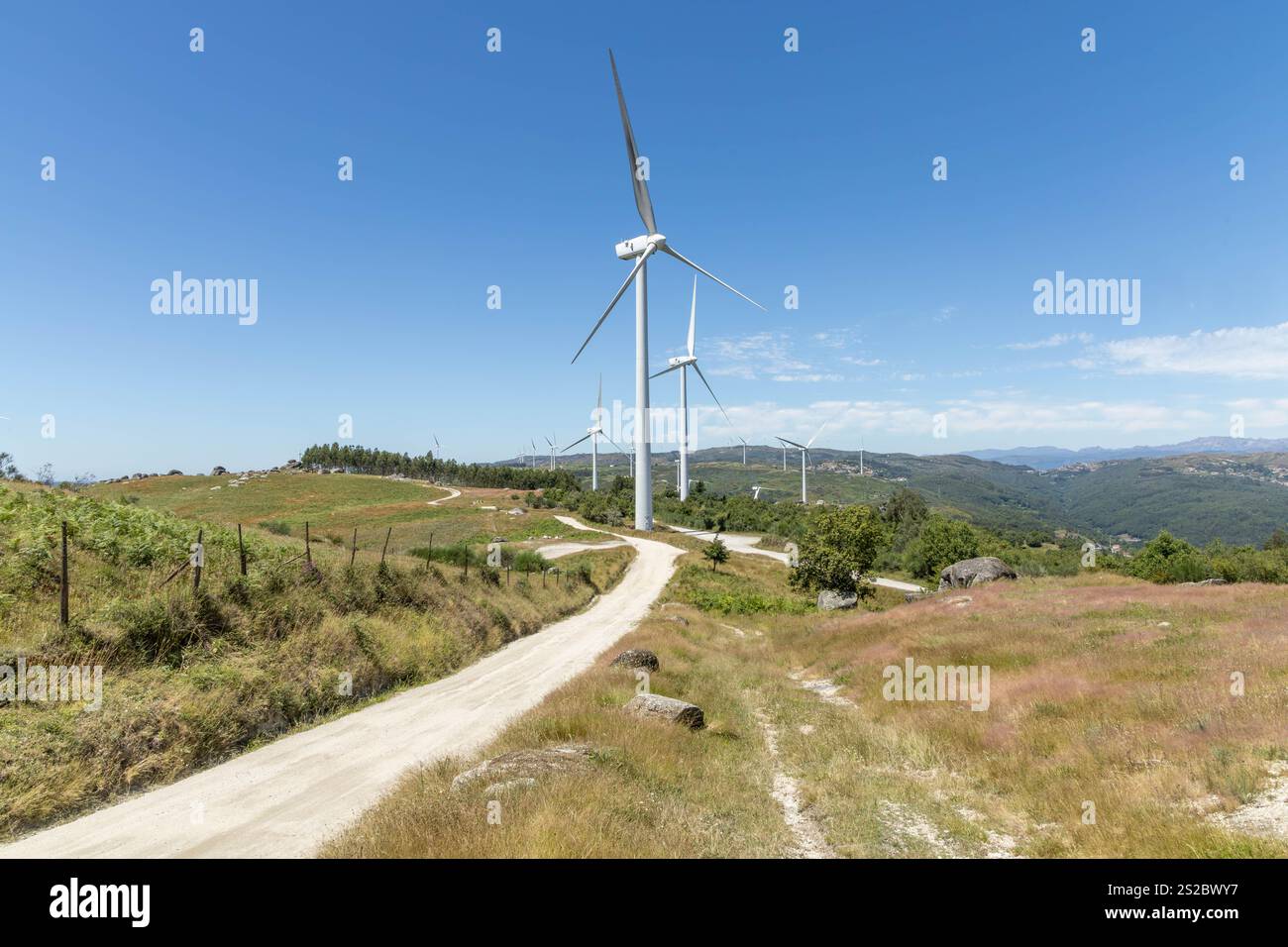 Grands moulins à vent modernes sur les montagnes avec route déserte et ciel bleu dans la région de Fafe au Portugal Banque D'Images