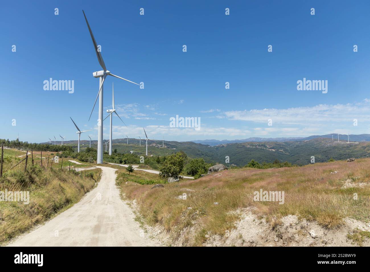 Plusieurs grands moulins à vent modernes sur les montagnes avec route déserte et ciel bleu dans la région de Fafe au Portugal Banque D'Images