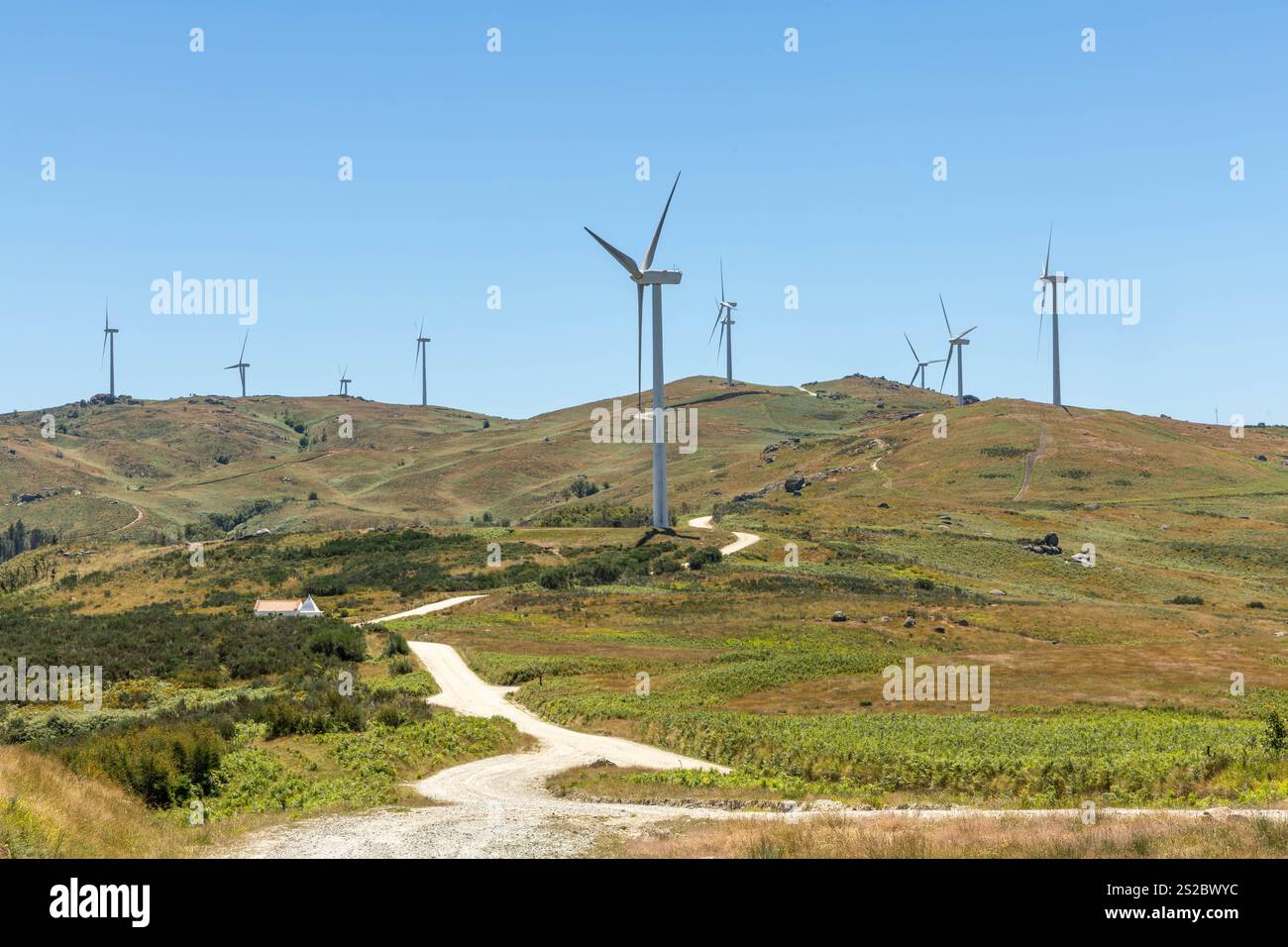Plusieurs grandes éoliennes modernes sur les montagnes avec route déserte et ciel bleu dans la région de Fafe au Portugal Banque D'Images