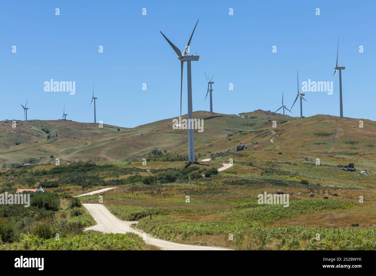 Grands moulins à vent modernes sur les collines avec route déserte et ciel bleu dans la région de Fafe au Portugal Banque D'Images