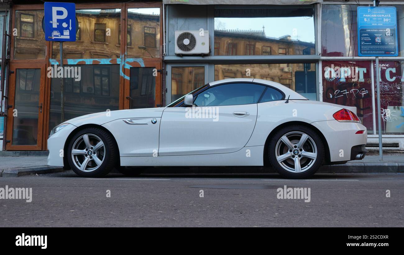 Bucarest, Roumanie – 6 janvier 2025 : gros plan de côté de la BMW Z4 voiture de luxe blanche avec vue de bâtiments abandonnés sur le fond Banque D'Images