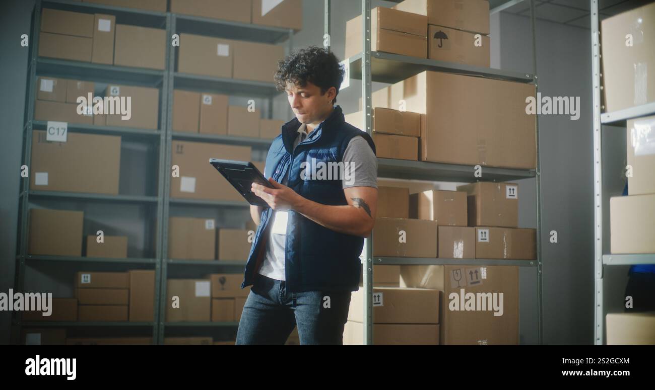 Mouvement lent du coordinateur logistique masculin avec une tablette électronique donnant des instructions de livraison aux collègues. Employés d'entrepôt multiethnique travaillant dans le centre de tri du service postal ou magasin en ligne. Banque D'Images
