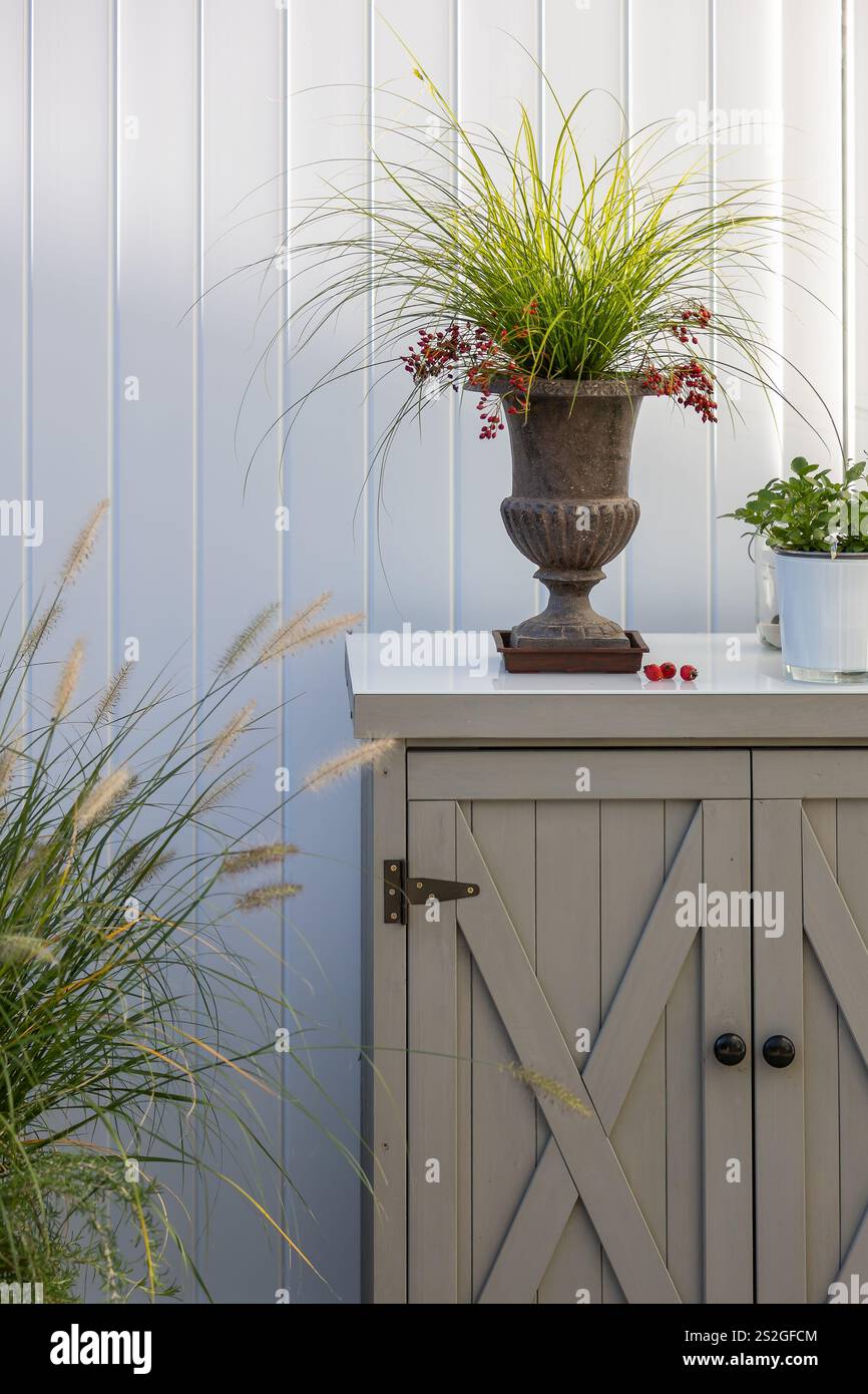 Une petite armoire sur une terrasse devant un séparateur blanc avec différentes décorations Banque D'Images
