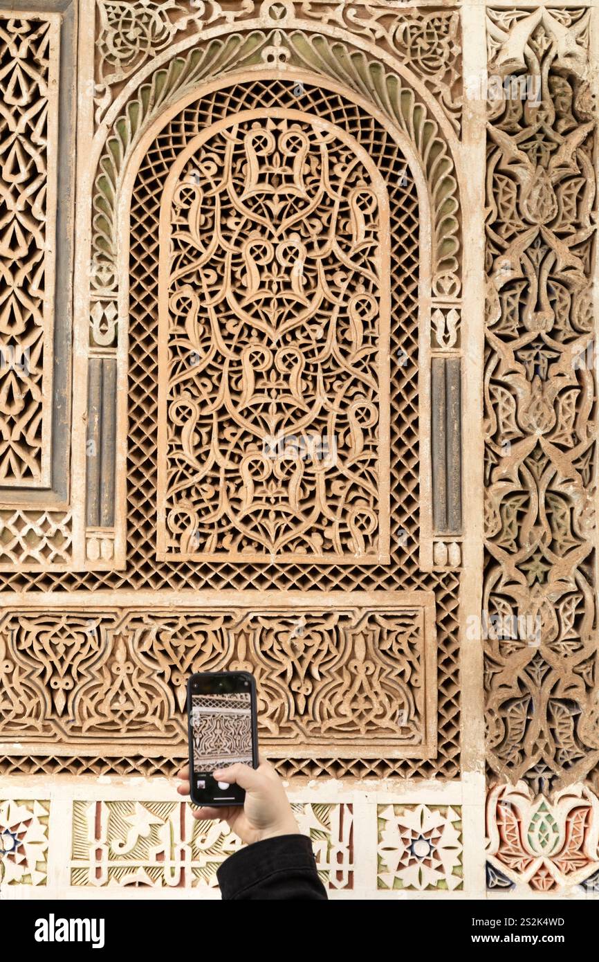 Un touriste photographie les détails d'un mur orné à Marrakech, Maroc. Le motif complexe est un exemple de plâtre Tadelakt. Banque D'Images