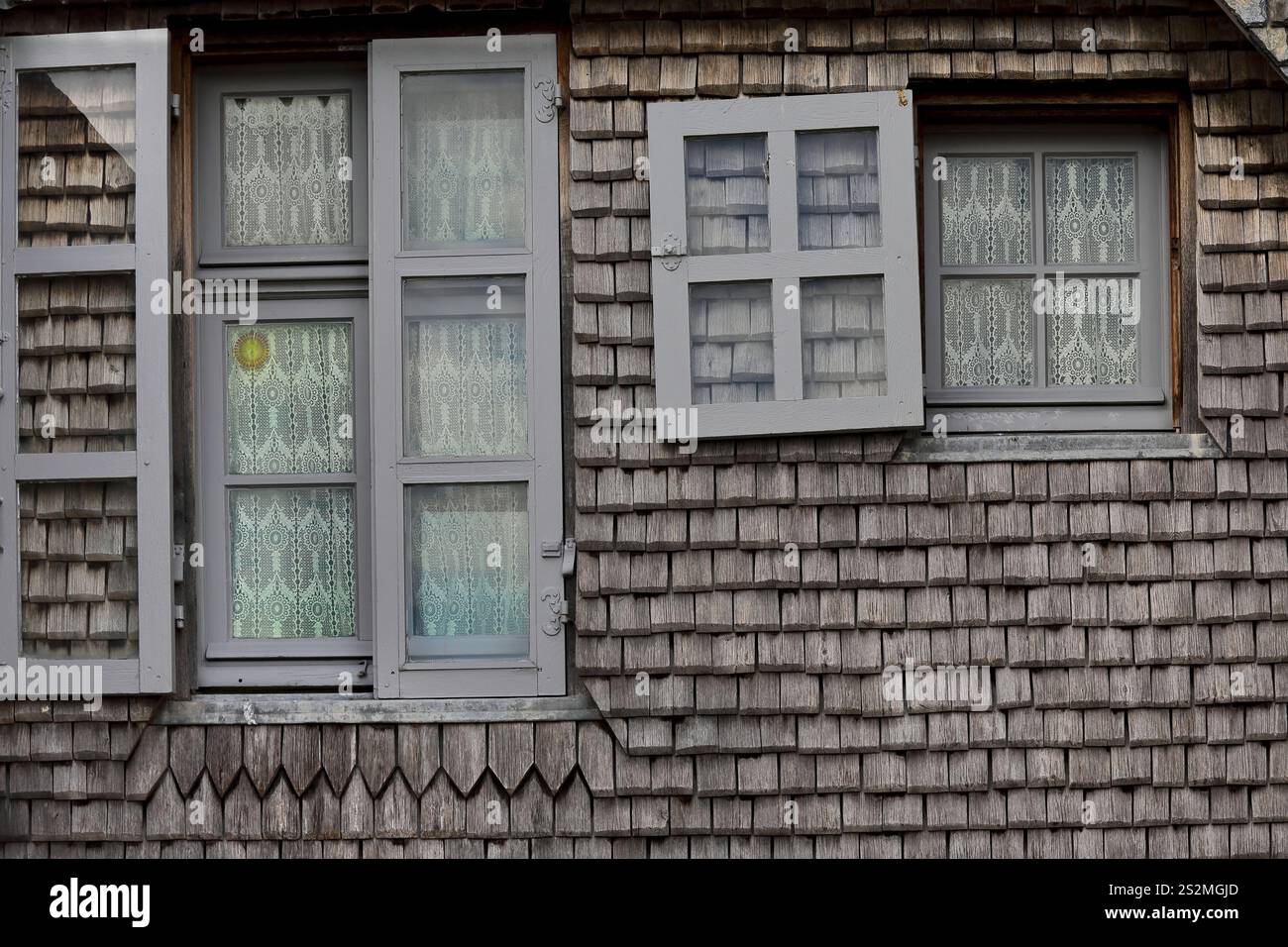 162 Mont-Saint-Michel : rideaux en crochet sur baies vitrées grises, façade arrière revêtue de bois de maison du XVe siècle, mur-promenade du rempart. Normandie-France. Banque D'Images