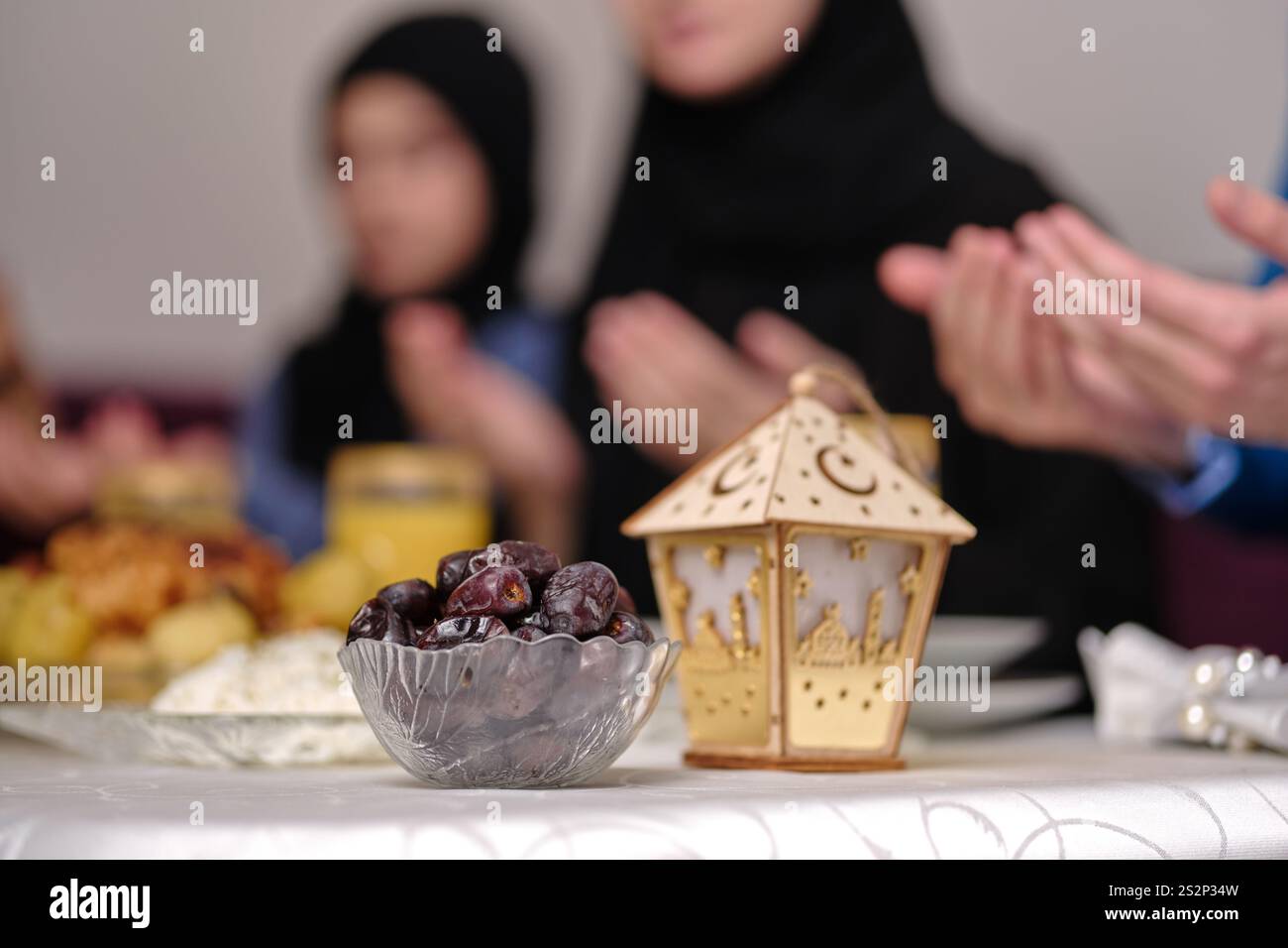 Heureuse famille musulmane ensemble faisant iftar dua pour faire la pause jeûne pendant le Ramadan à la table à manger à la maison se concentrer sur un bol de dates. Banque D'Images