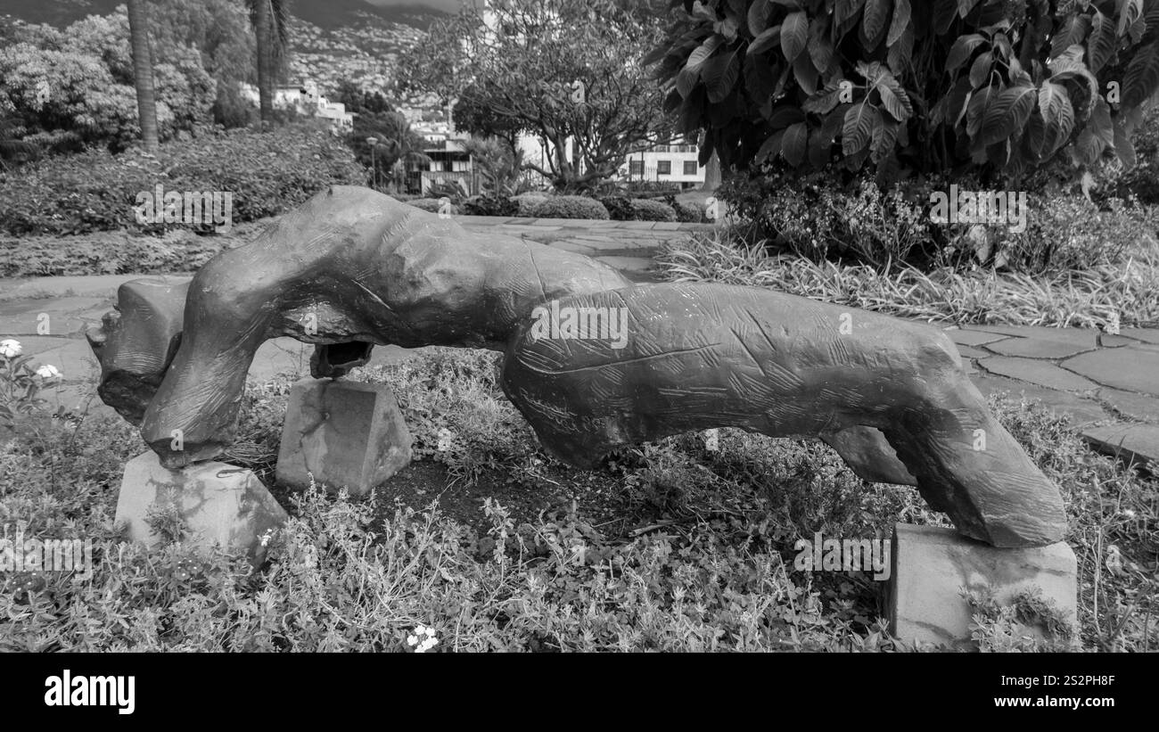 Photo en noir et blanc d'une sculpture moderne représentant une figure humaine dans une pose rampante, exposée dans un parc luxuriant entouré d'arbres et de végétation Banque D'Images Photo en noir et blanc d'une sculpture moderne représentant une figure humaine dans une pose rampante, exposée dans un parc luxuriant entouré d'arbres et de végétation Banque D'Images