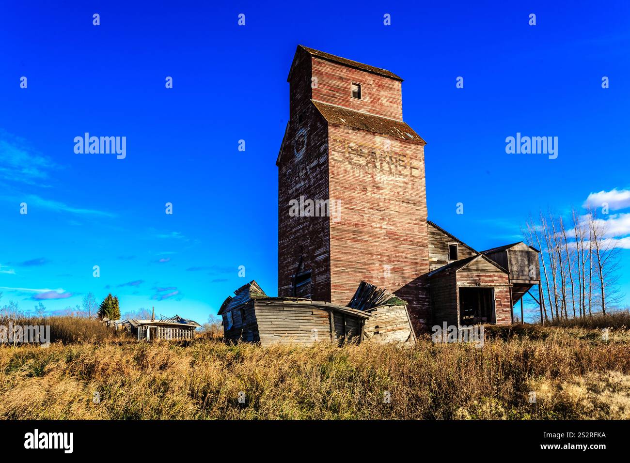 Un grand bâtiment en briques avec un toit rouge se trouve dans un champ. Le ciel est clair et bleu Banque D'Images