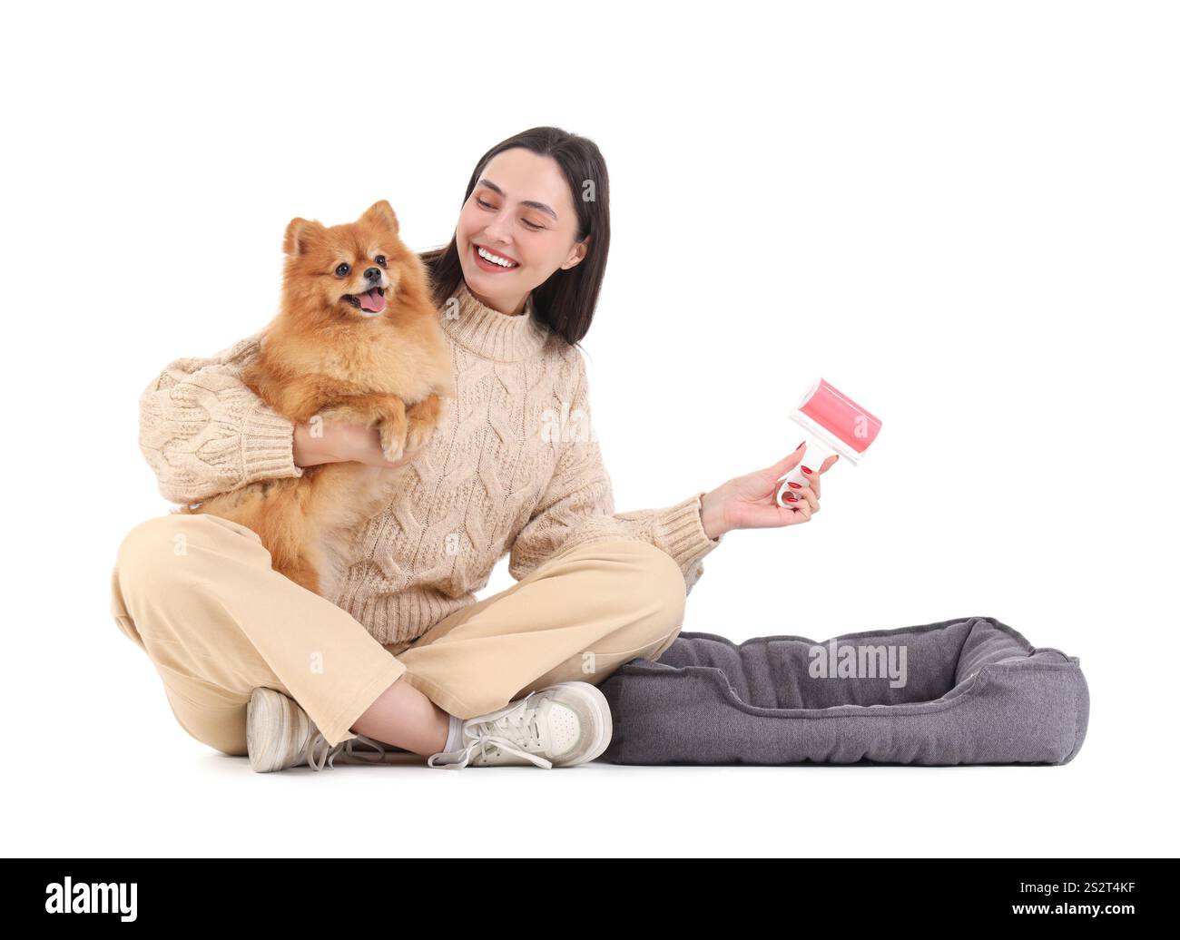 Jeune femme avec chien moelleux, lit d'animal de compagnie et rouleau de peluche sur fond blanc Banque D'Images