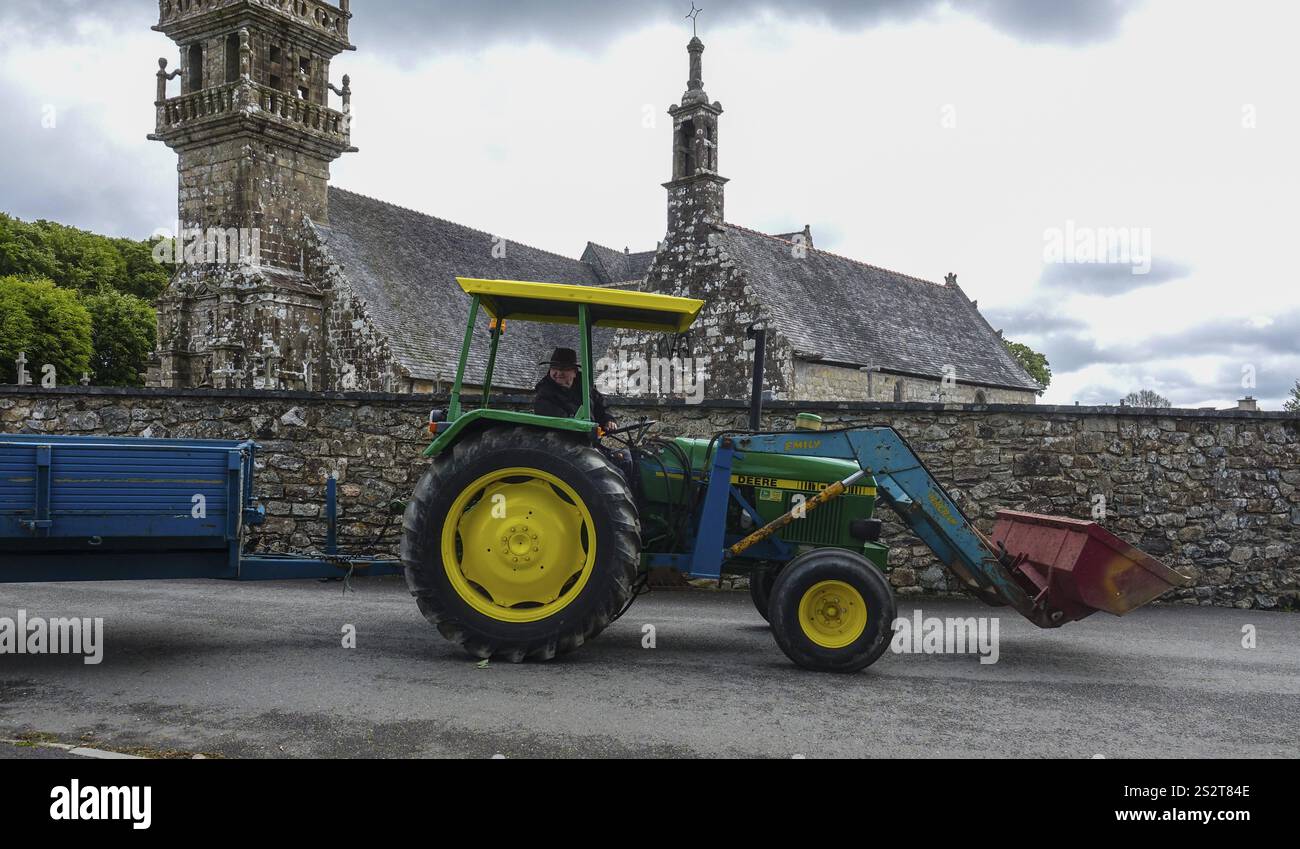 Vieux tracteur John Deere 1040 avec remorque devant l'église et la chapelle Sainte nonne, voiture ancienne rencontre Dirinon, département Finistère Penn Ar Bed, Re Banque D'Images