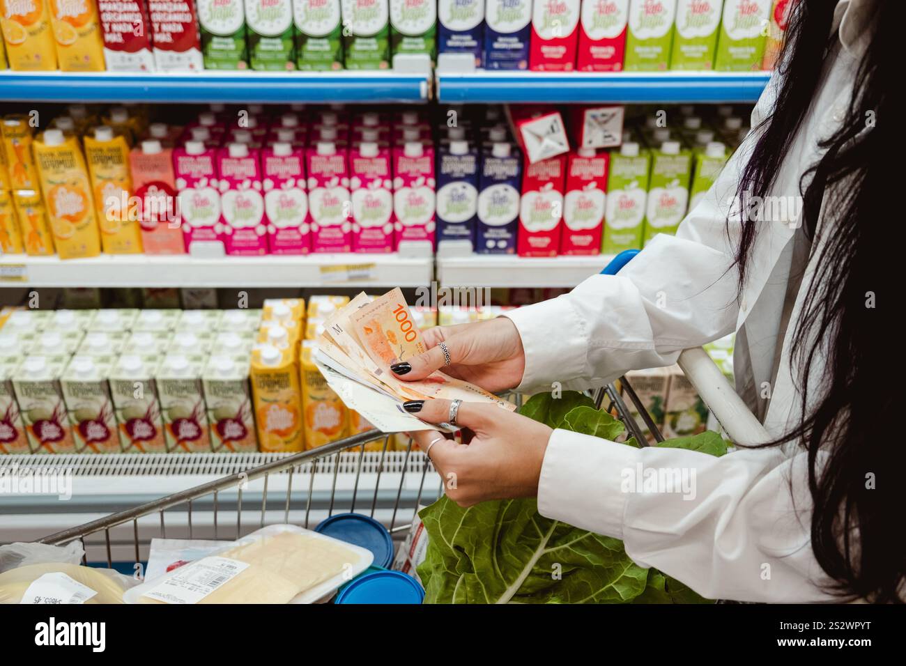 Femme achetant de la nourriture et comptant de l'argent - Pesos argentins - dans le supermarché. Concept lié à l'inflation et à la crise économique Banque D'Images